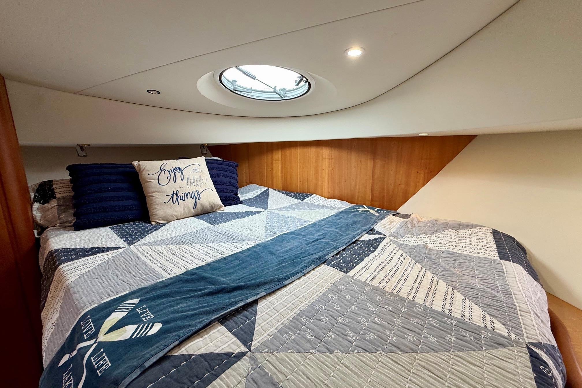 Cozy bedroom in 2004 Silverton 39 Motor Yacht with quilted bedding and decorative pillows.