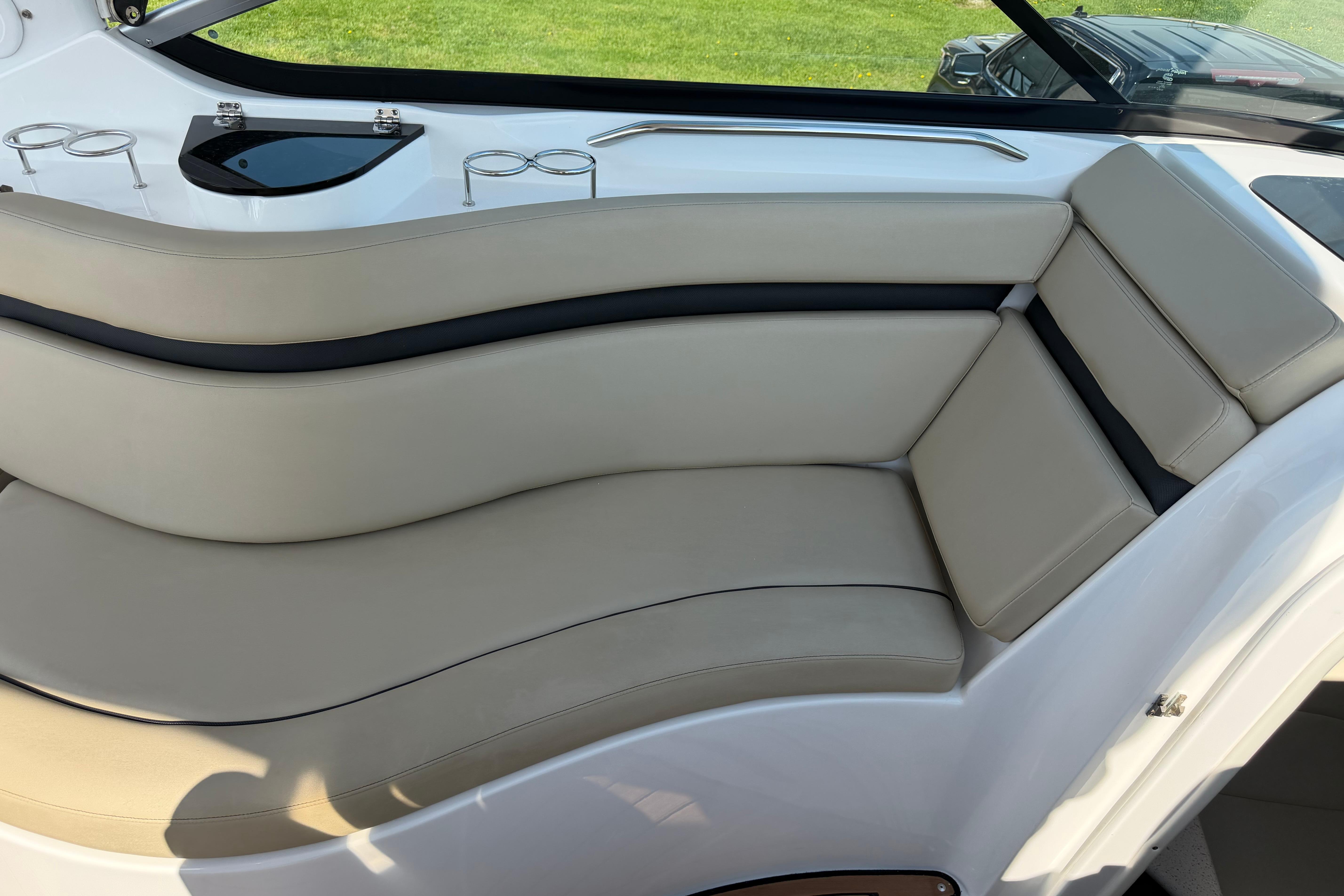 Luxurious seating on a 2019 Rinker EX 320 boat, featuring beige upholstery and cup holders.