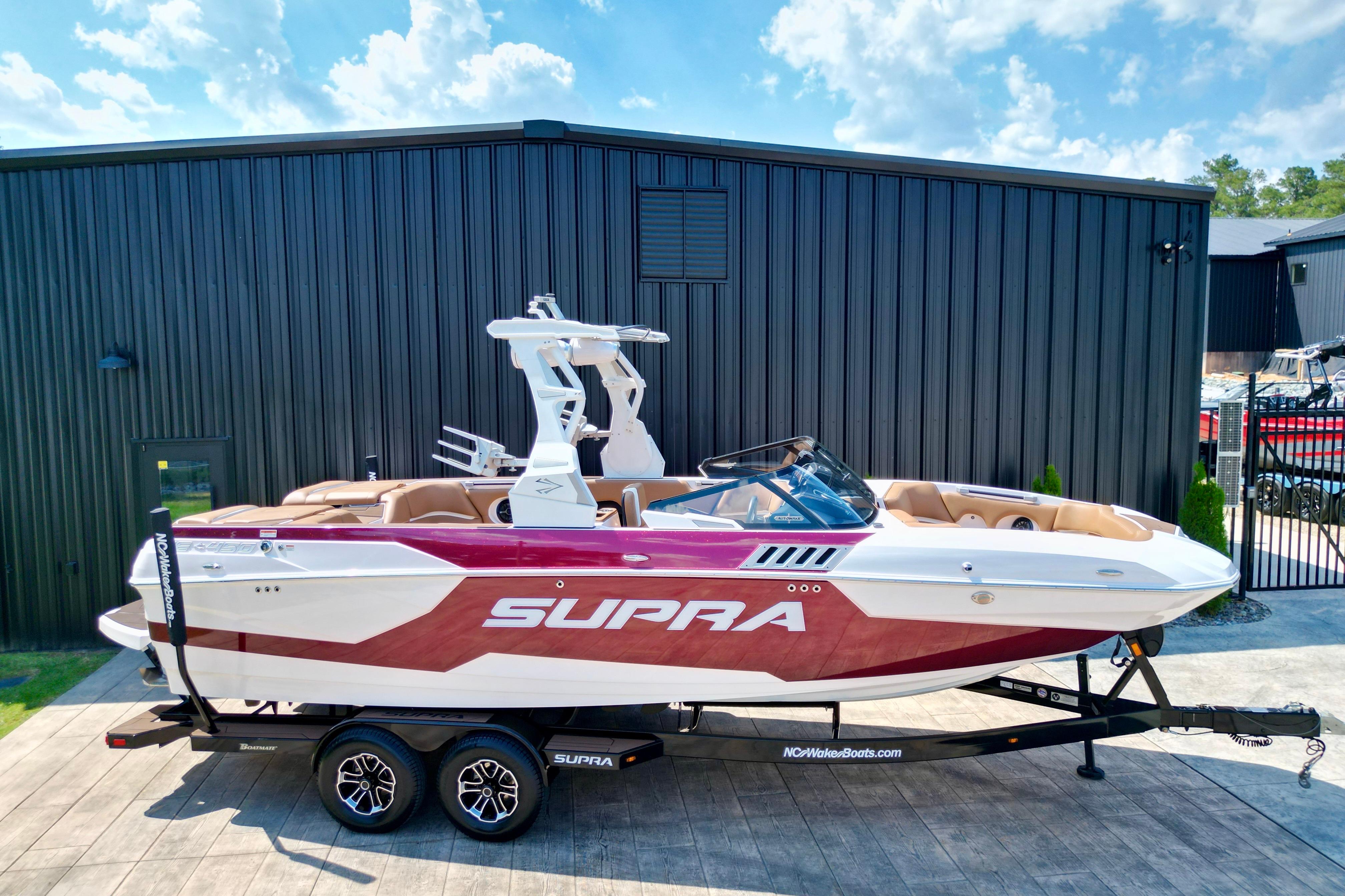 2021 Supra SE boat on trailer, sleek design, parked outdoors under blue sky.