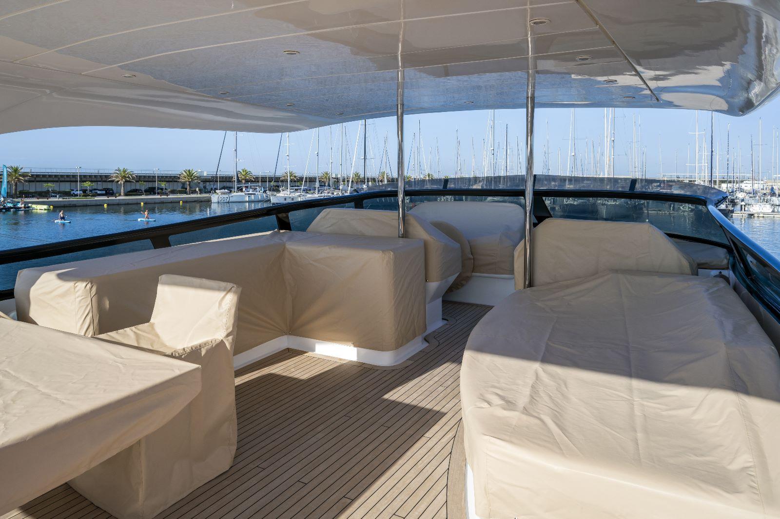 Luxurious 2011 Maiora 27 yacht deck with covered seating and scenic marina view.
