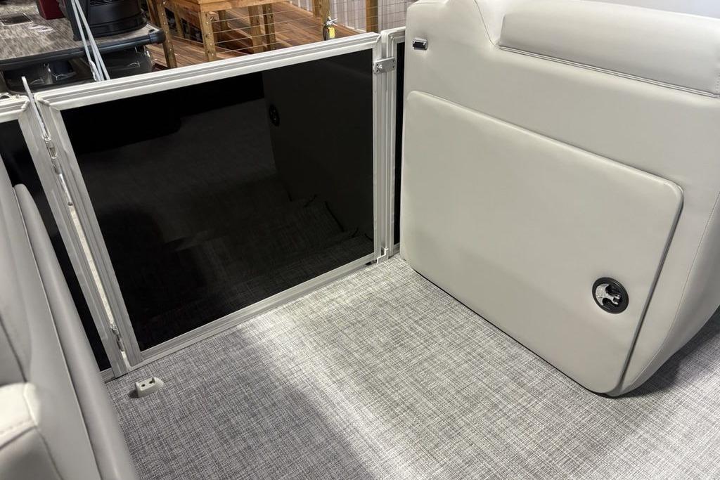 2026 Sun Tracker PARTY BARGE® 20 DLX interior with open storage compartment and gray flooring.