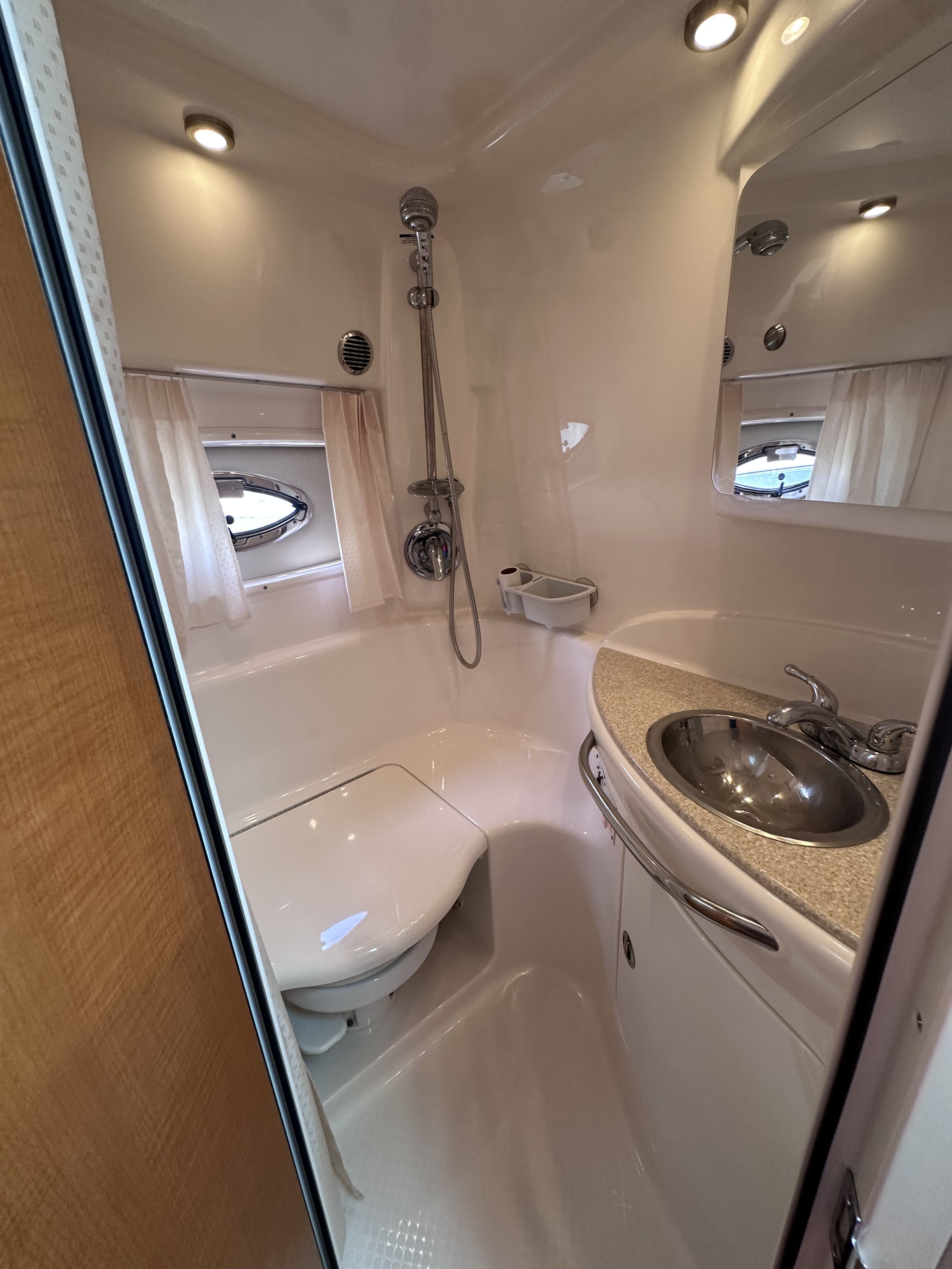 The image shows a sleek boat bathroom with a shower, sink, and toilet.