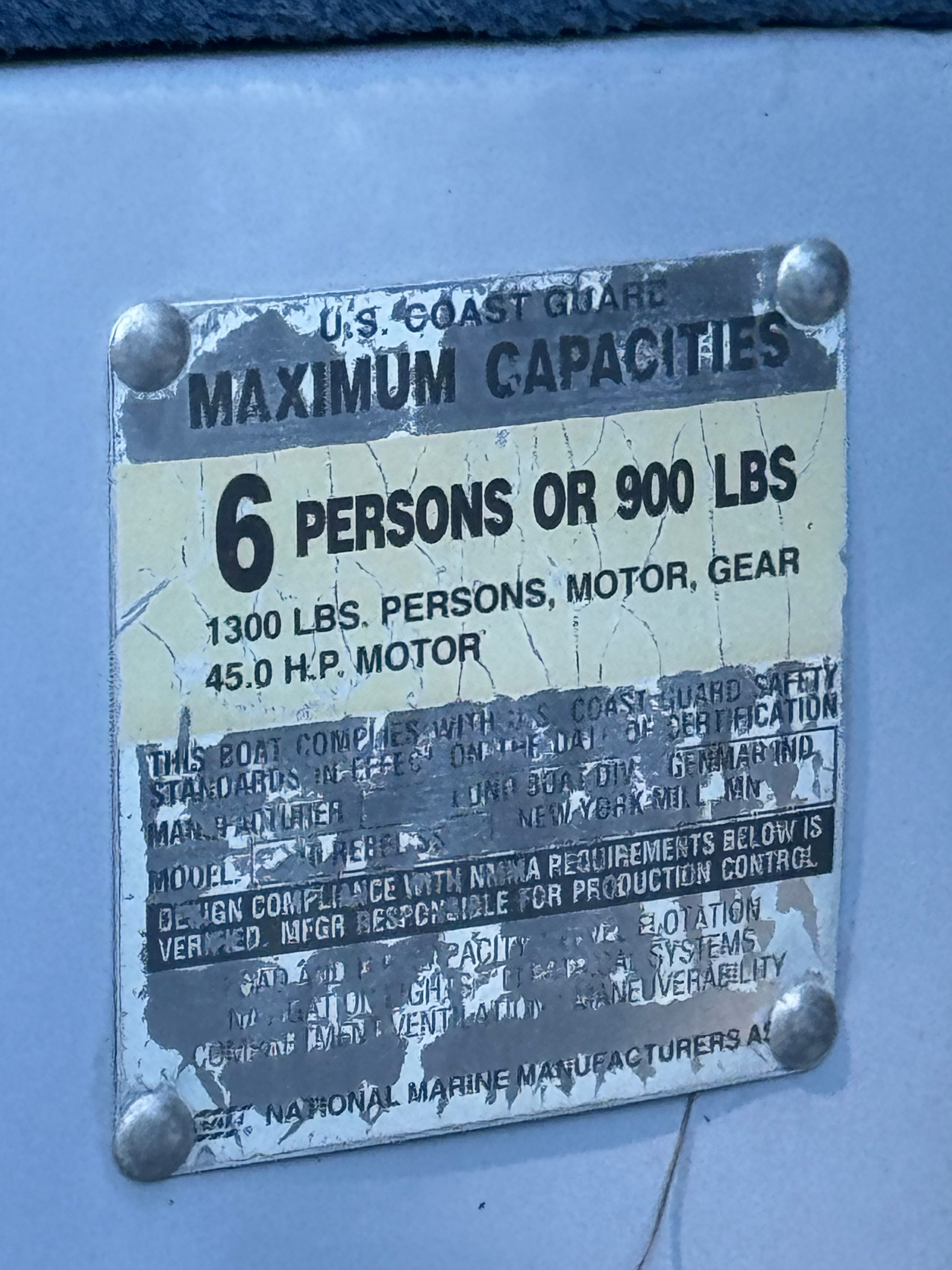 A sign shows the maximum capacity of a boat: 6 persons or 900 pounds.