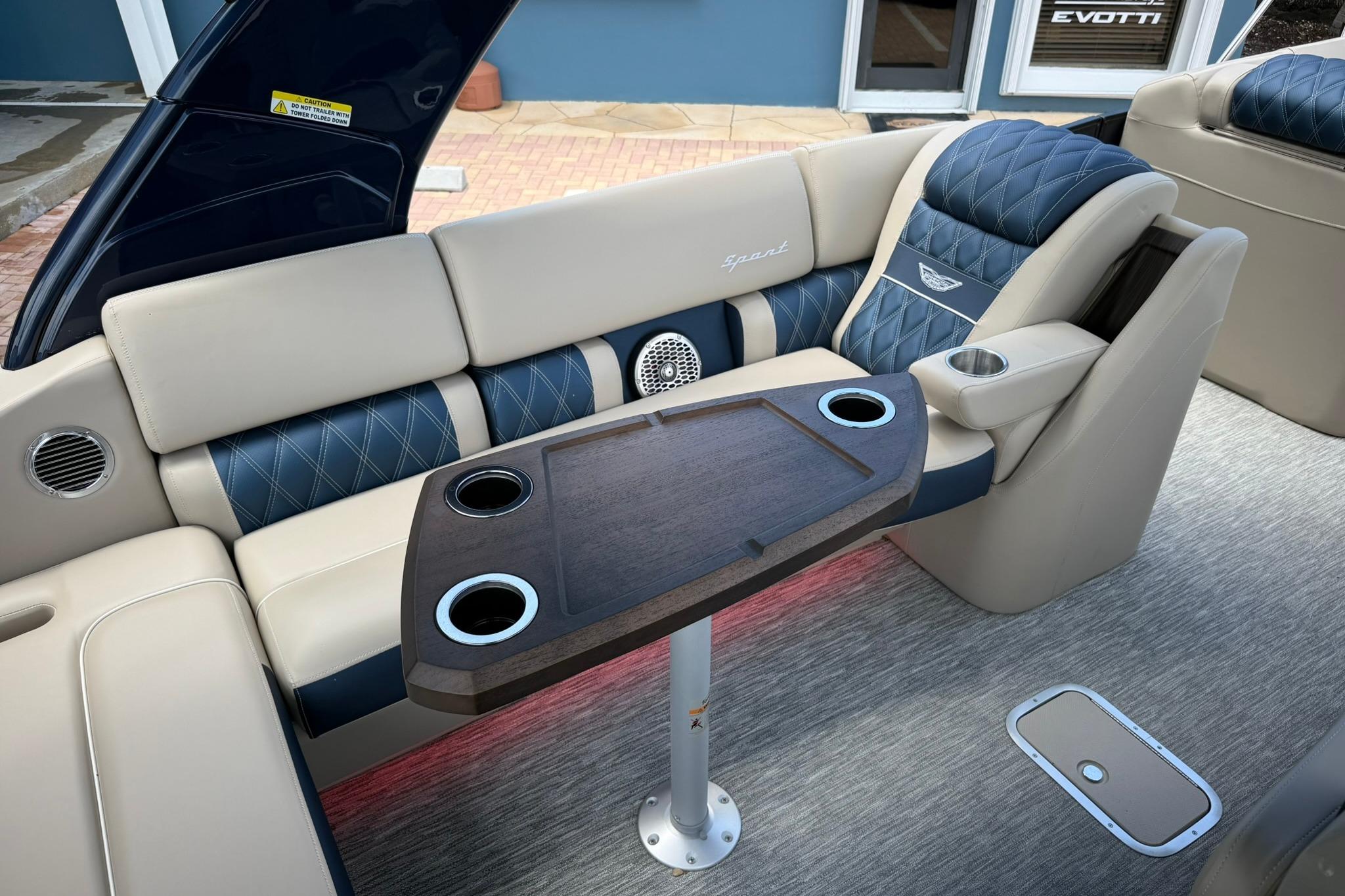 Luxurious seating area on 2026 Bennington 27 QSBAT2 pontoon boat with elegant table and cup holders.