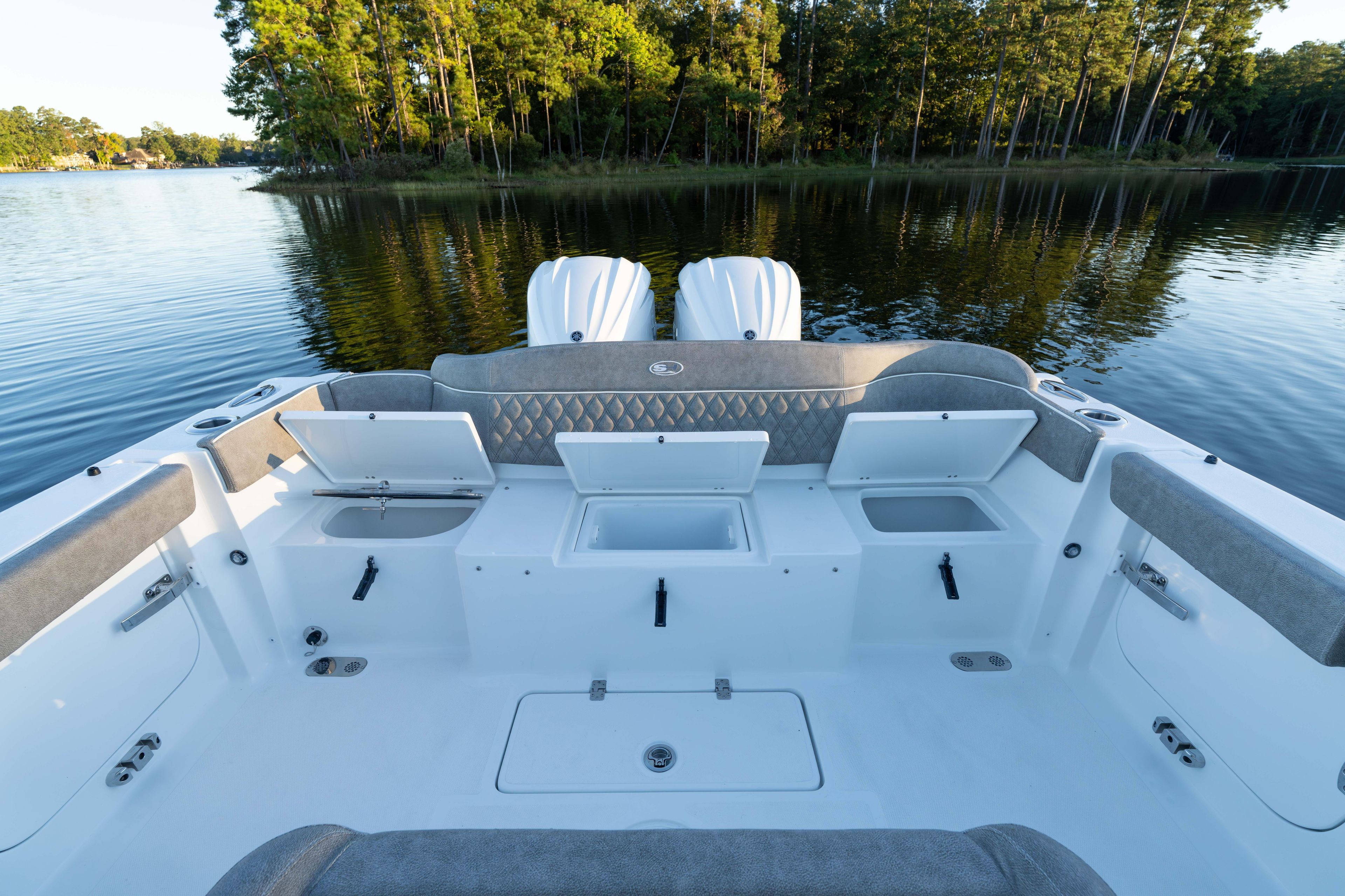 2026 Sea Hunt Ultra 275 Coffin Box boat interior with open storage compartments on a serene lake.