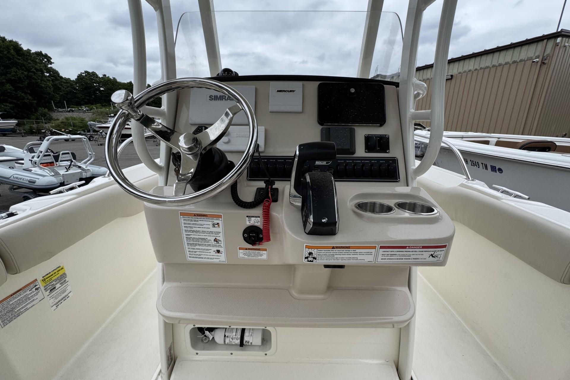 2024 Boston Whaler 230 Outrage boat console with steering wheel and controls.