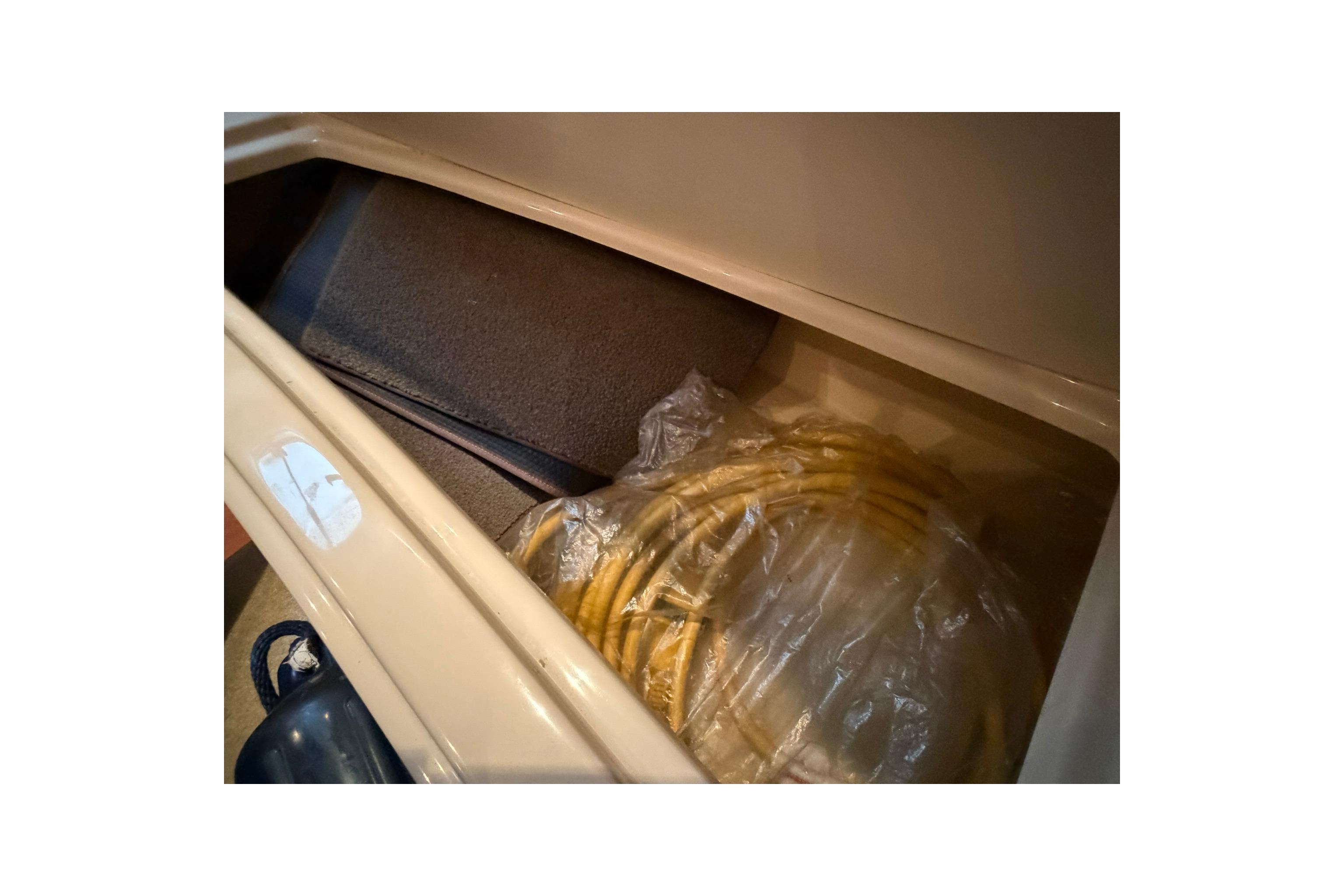 Storage compartment in 2008 Four Winns V248 boat with coiled yellow hose.