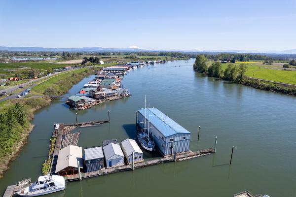 Aerial view of 1985 Custom Larson Boathouse on a serene river with surrounding greenery.
