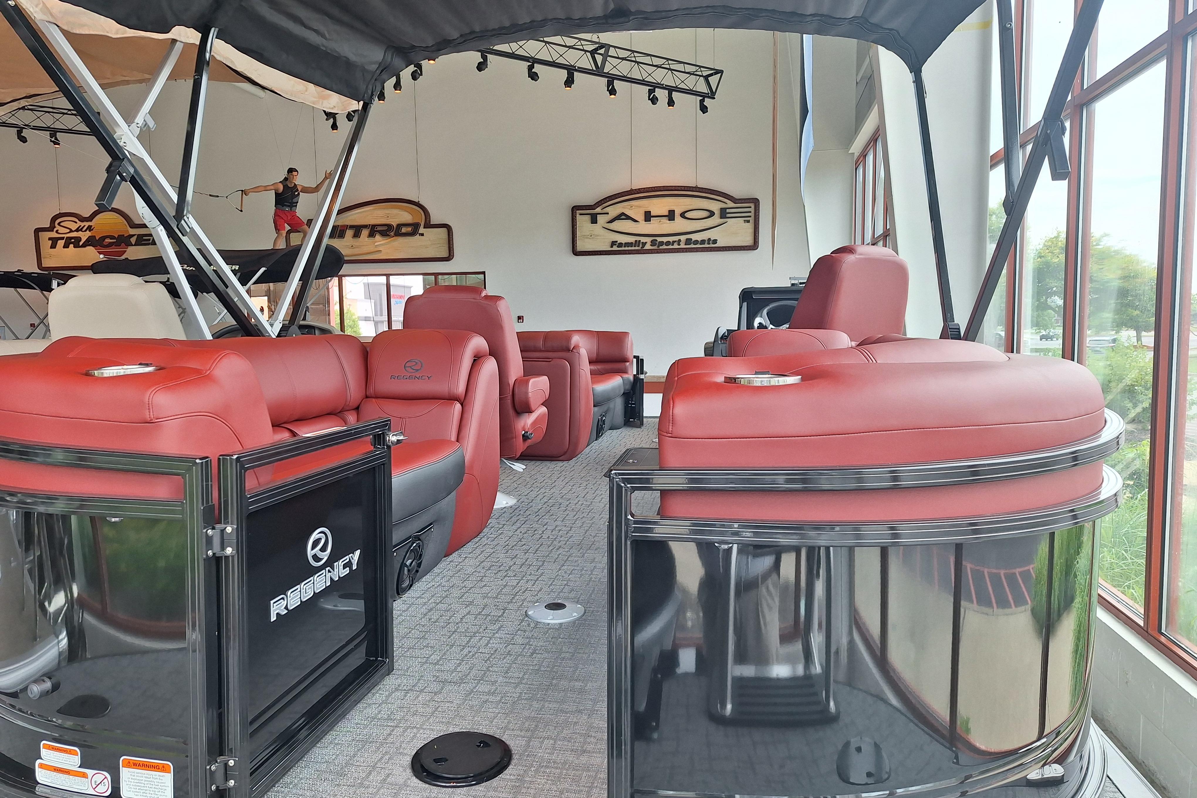 2026 Regency 230 DL pontoon boat with luxurious red seating in showroom display.