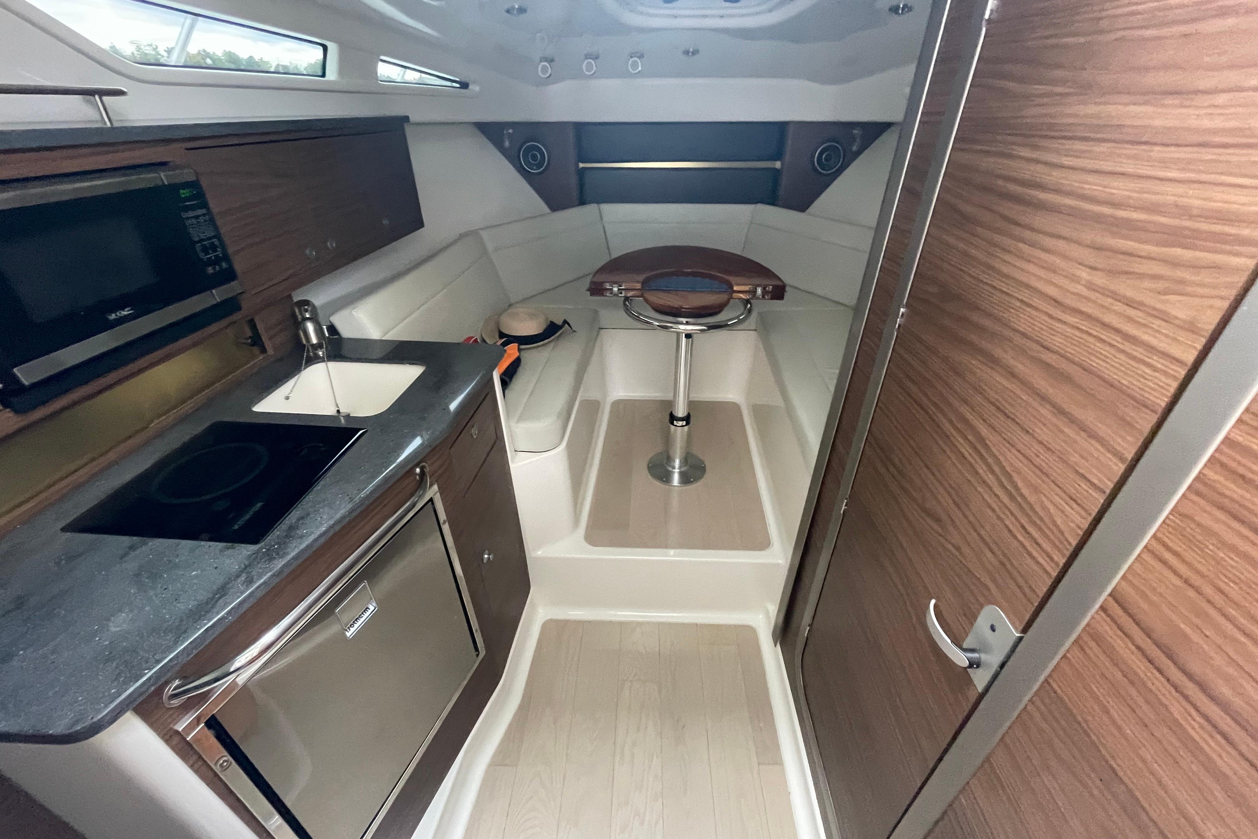 2023 Boston Whaler 325 Conquest cabin interior with kitchenette and seating area.