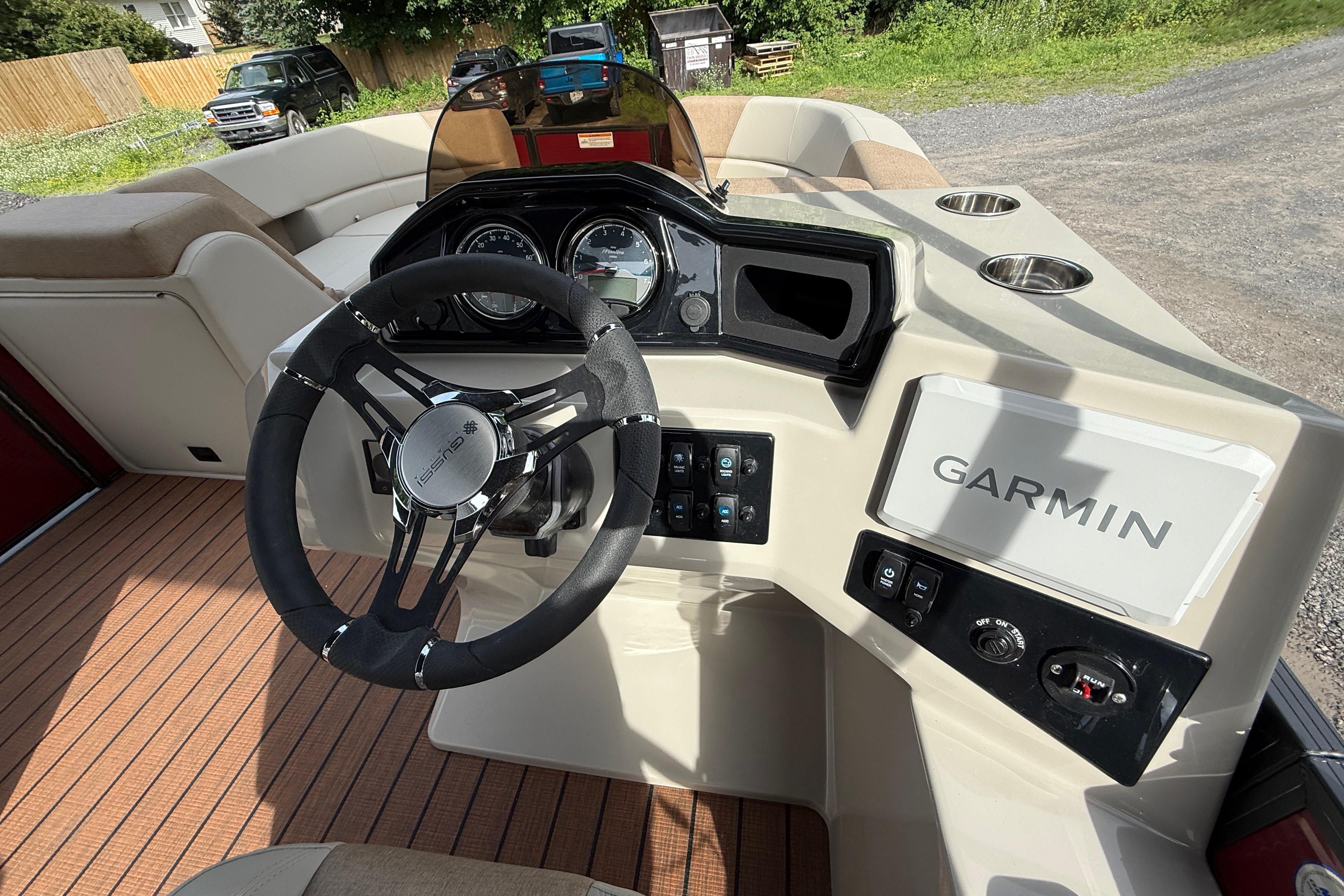 2027 Manitou 21 Aurora LE boat dashboard with Garmin navigation system and steering wheel.