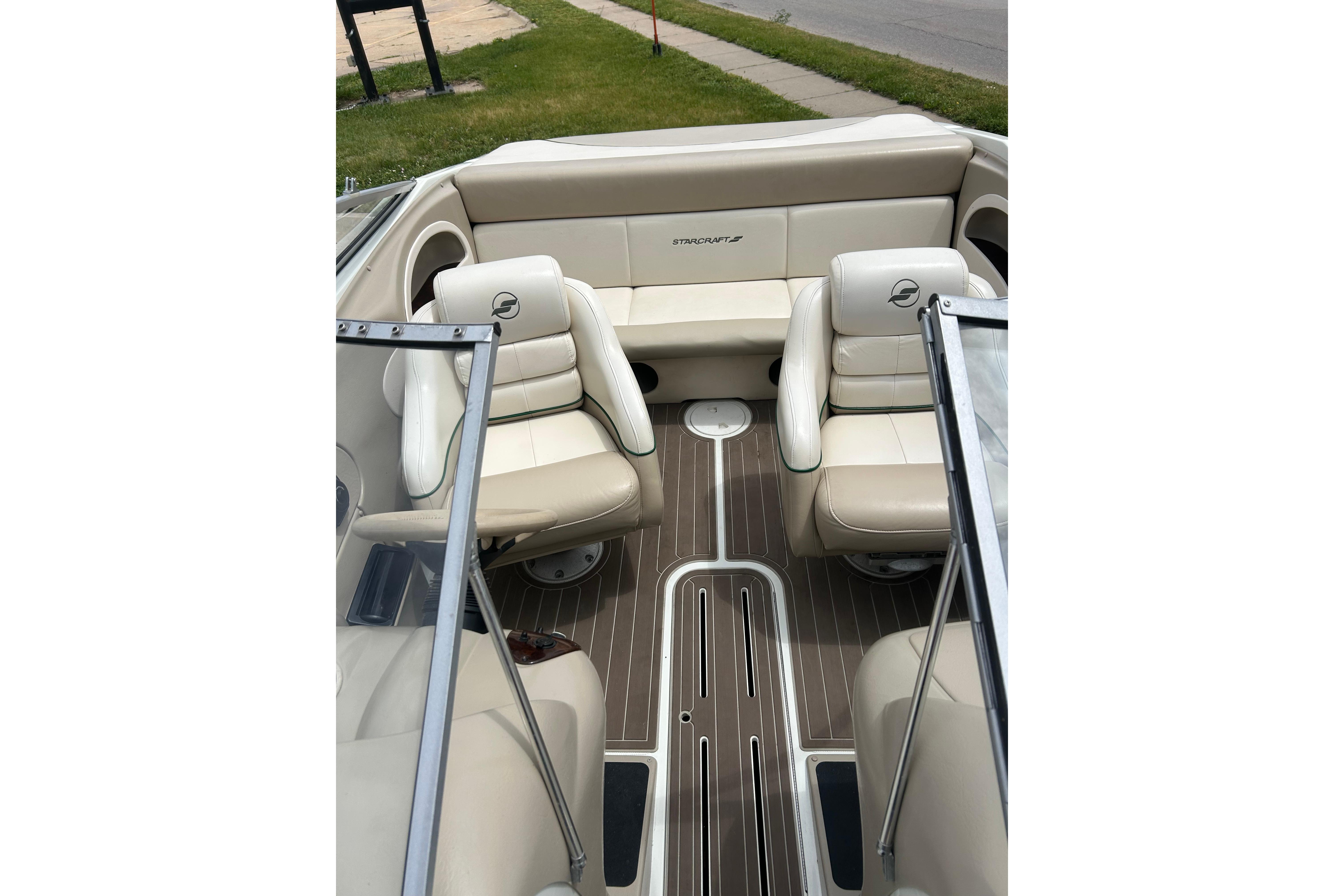Interior of a 2000 Starcraft 1810 boat with beige seating and wood-style flooring.