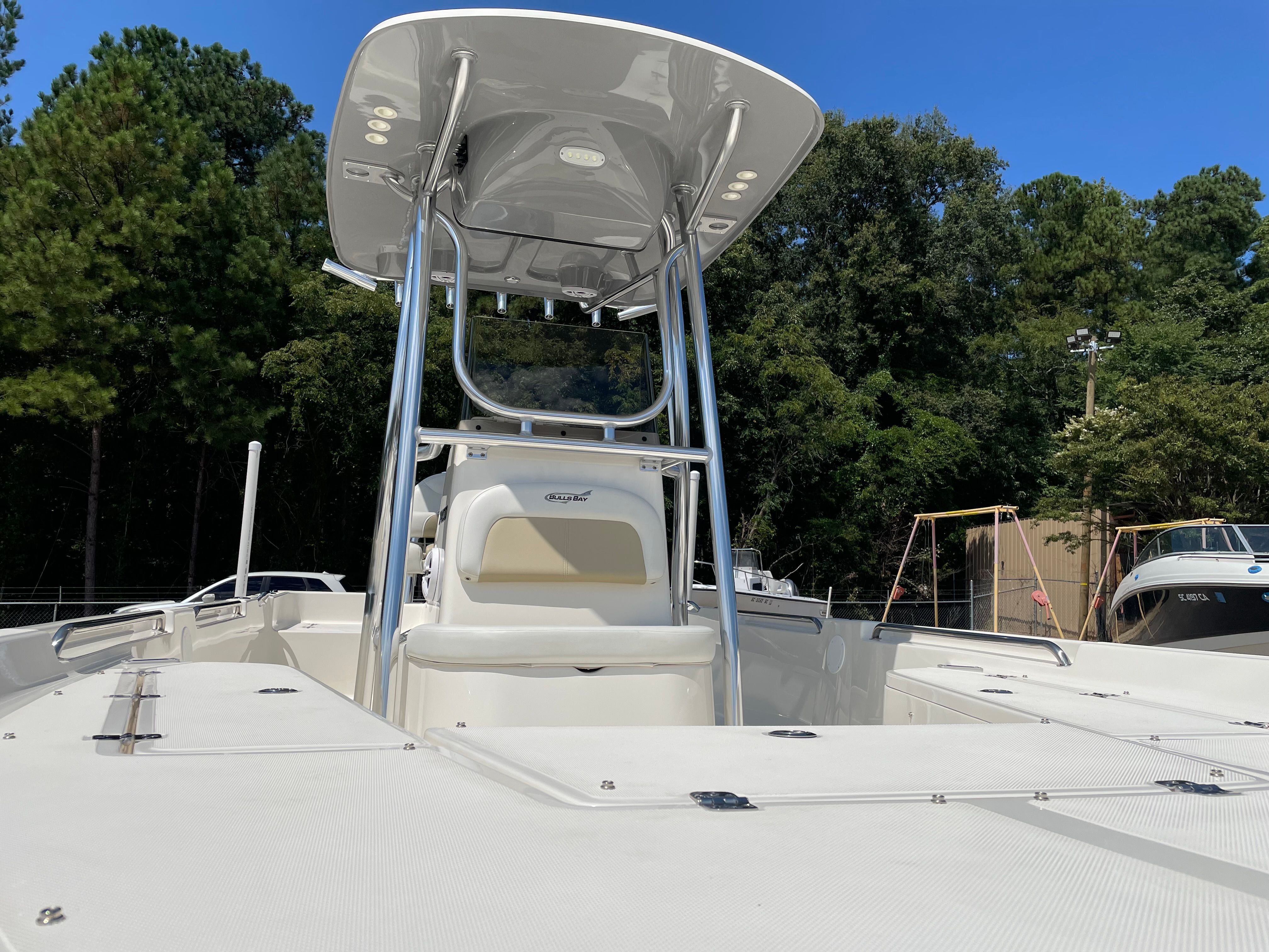 2023 Bulls Bay 2400 with T-top and spacious deck, surrounded by trees.