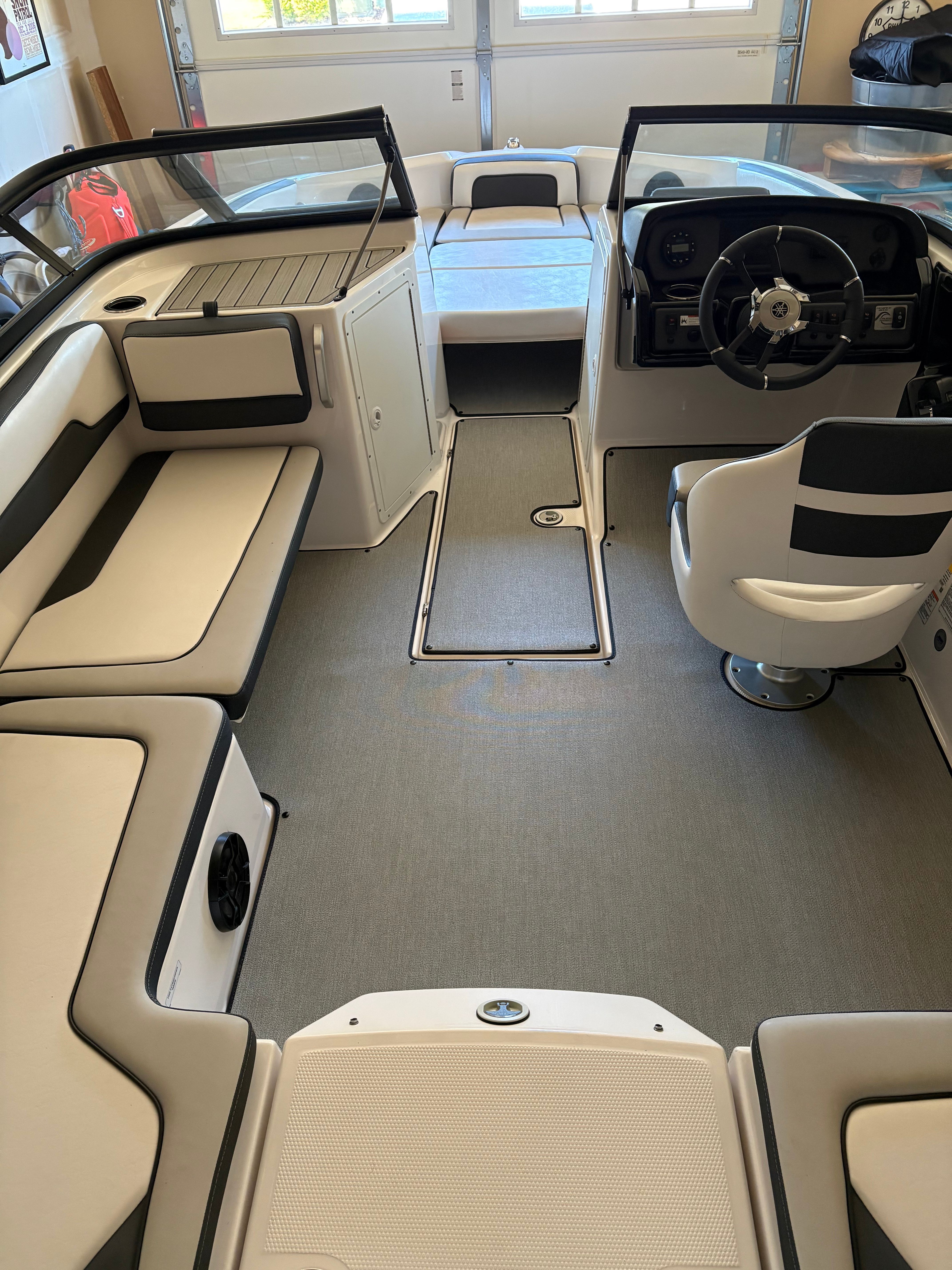 Interior of a Yamaha AR195 boat with white seating and steering wheel.