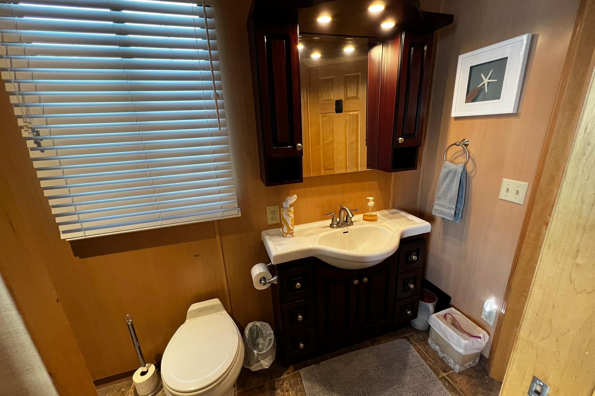 Bathroom interior of 2010 Skipperliner 480 Flybridge with sink, toilet, and wooden cabinetry.