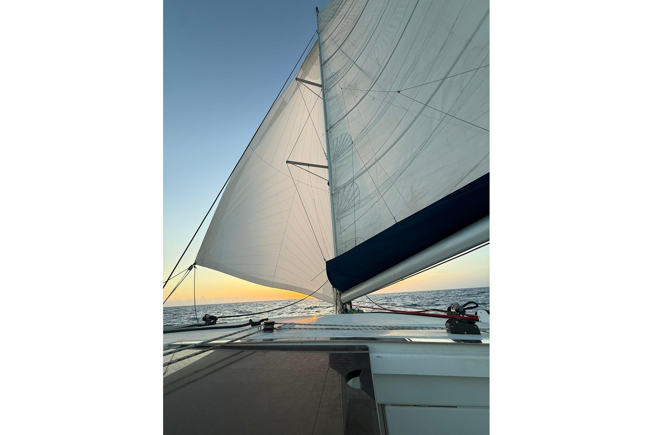 Sailing on a 2008 Fountaine Pajot Salina 48 catamaran at sunset.