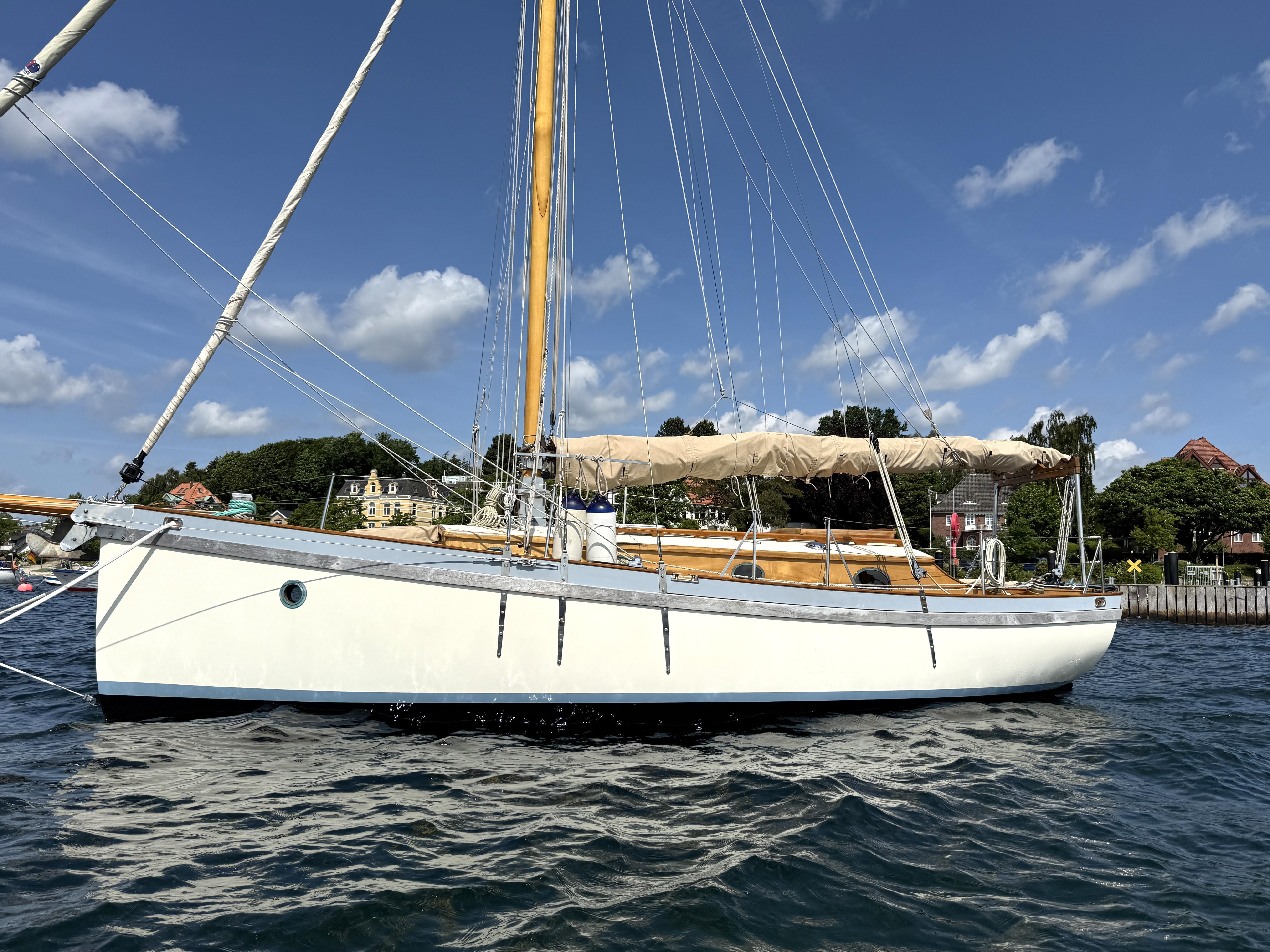 2010 Buccaneer Salcombe Trader 27 sailboat on water, clear sky background.