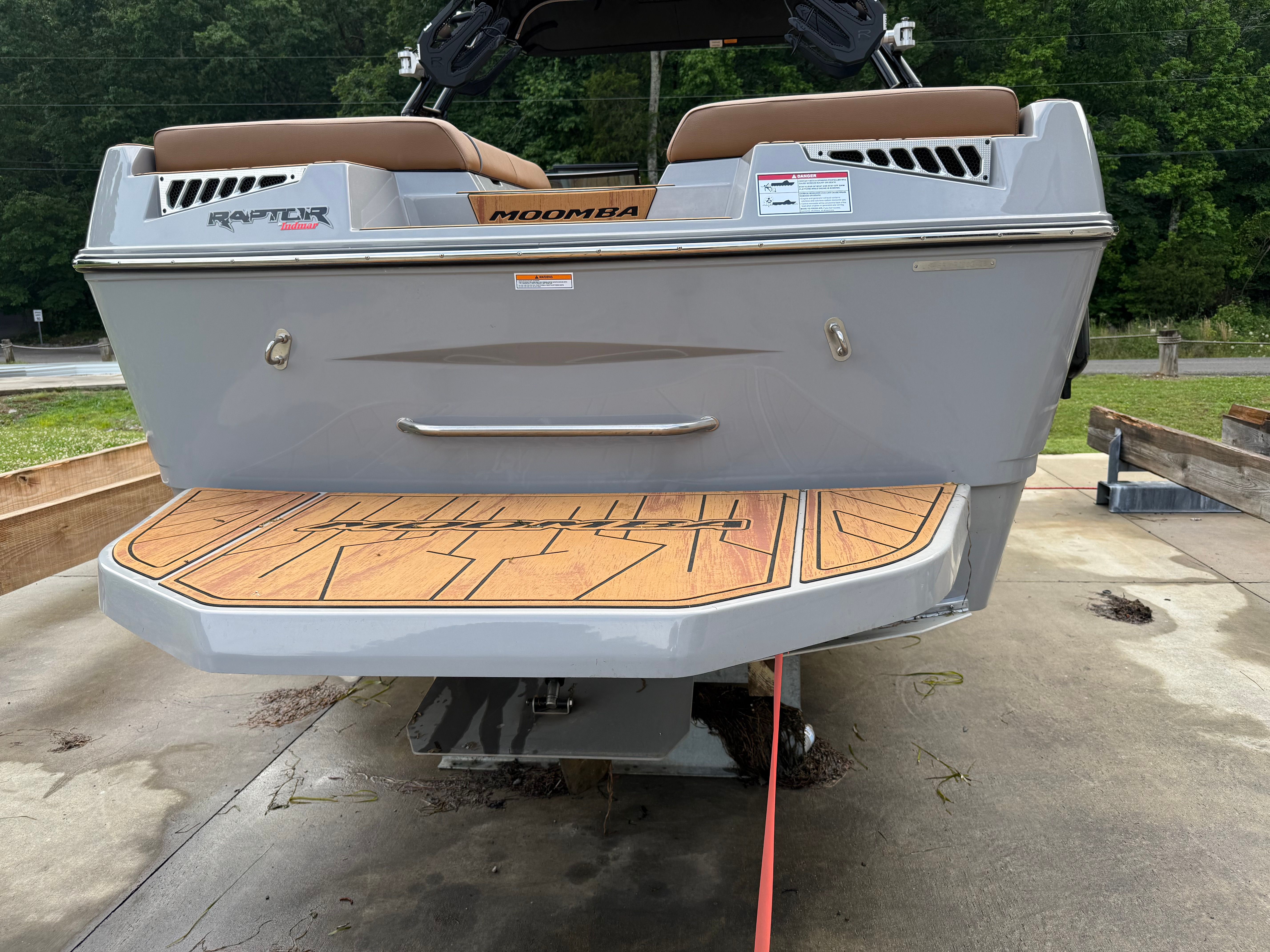 The image shows the rear of a 2025 Malibu Mojo boat with a wooden platform.
