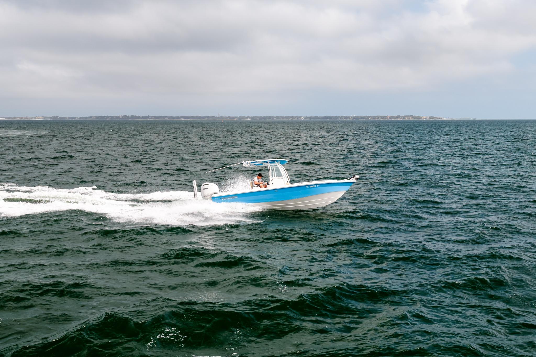 2023 Everglades 243 Center Console boat cruising on open water under cloudy skies.