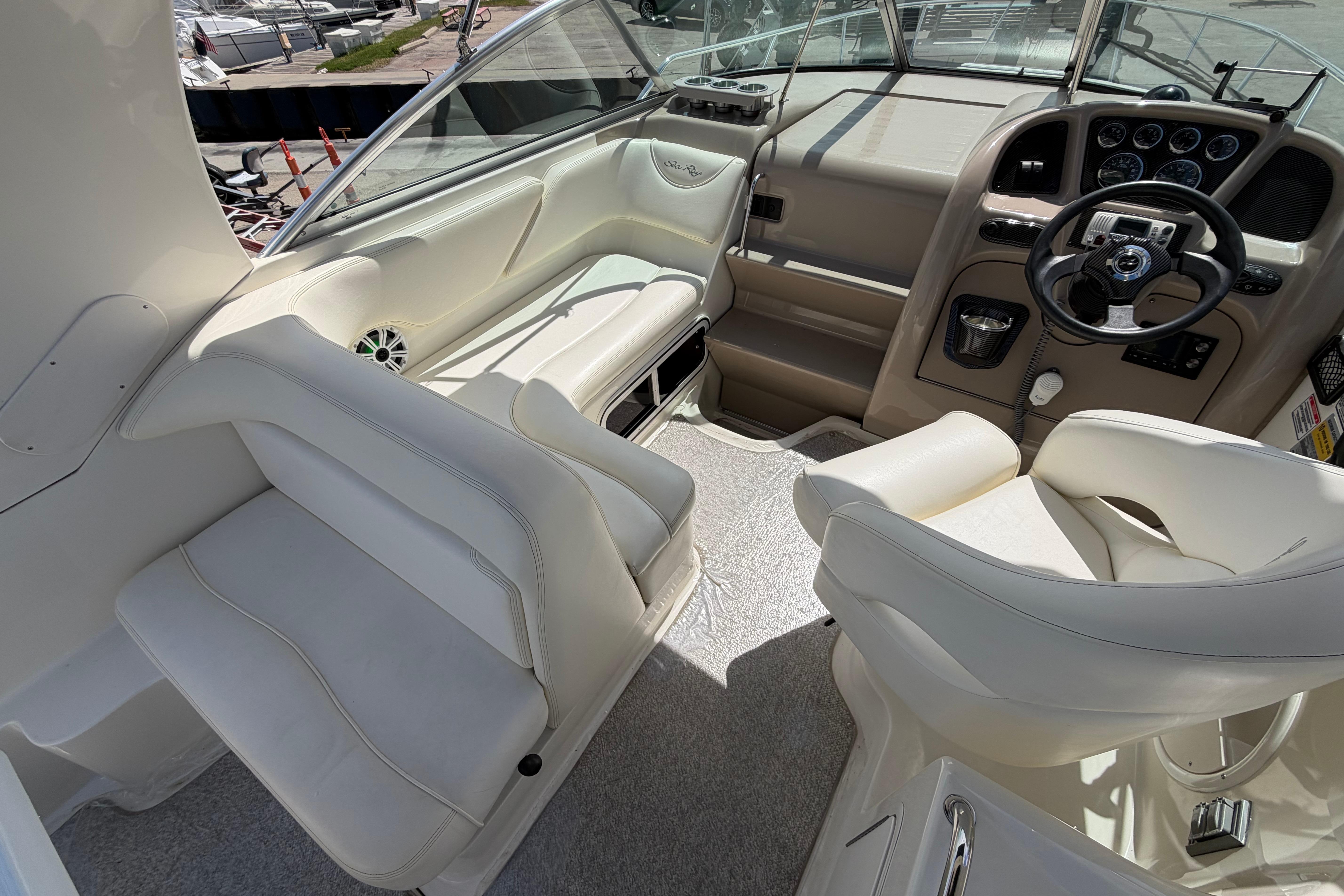 Interior of a 2004 Sea Ray Sundancer 260 boat with white seating and steering console.