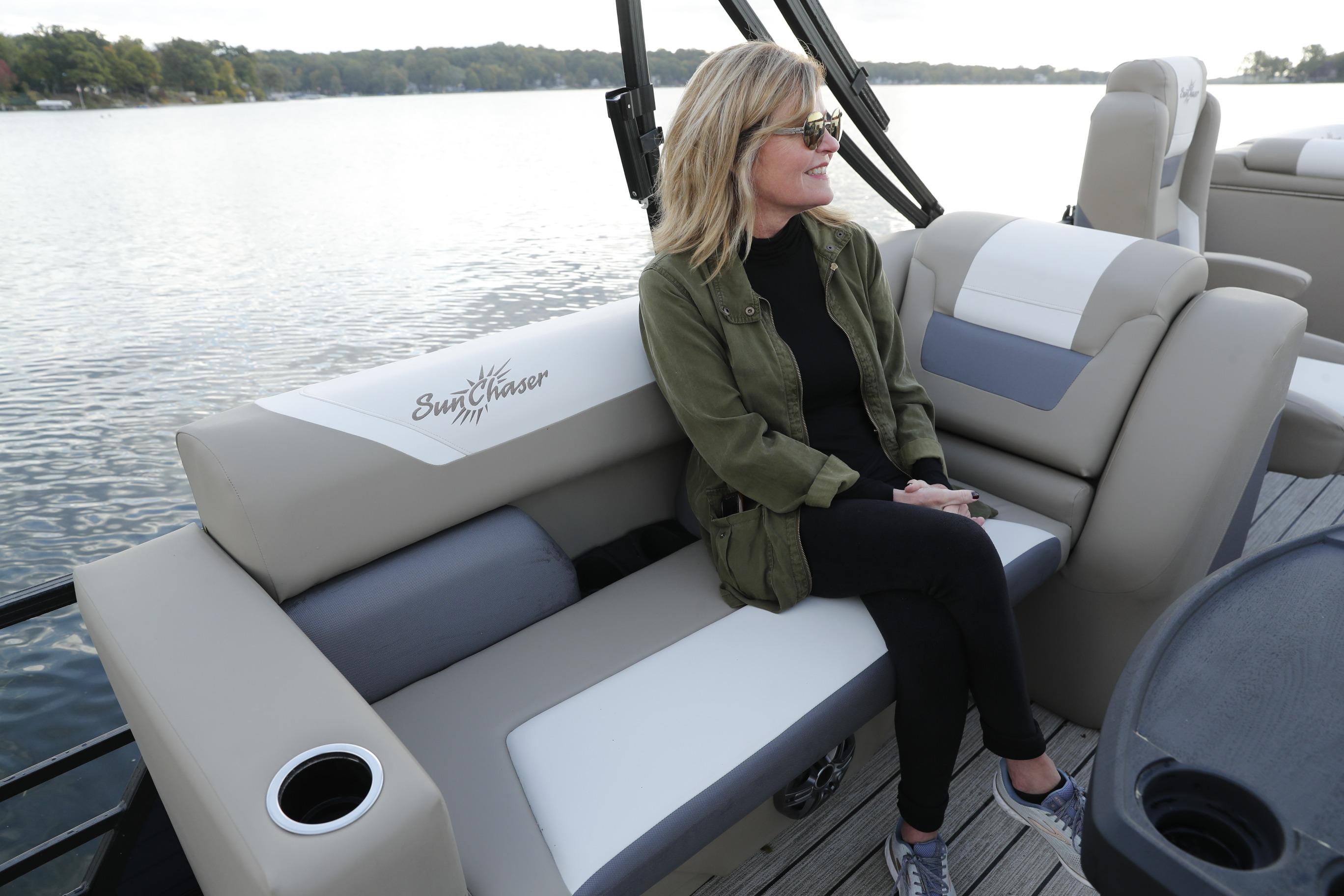 Woman relaxing on a 2026 SunChaser Eclipse 25 LR DH pontoon boat by a lake.