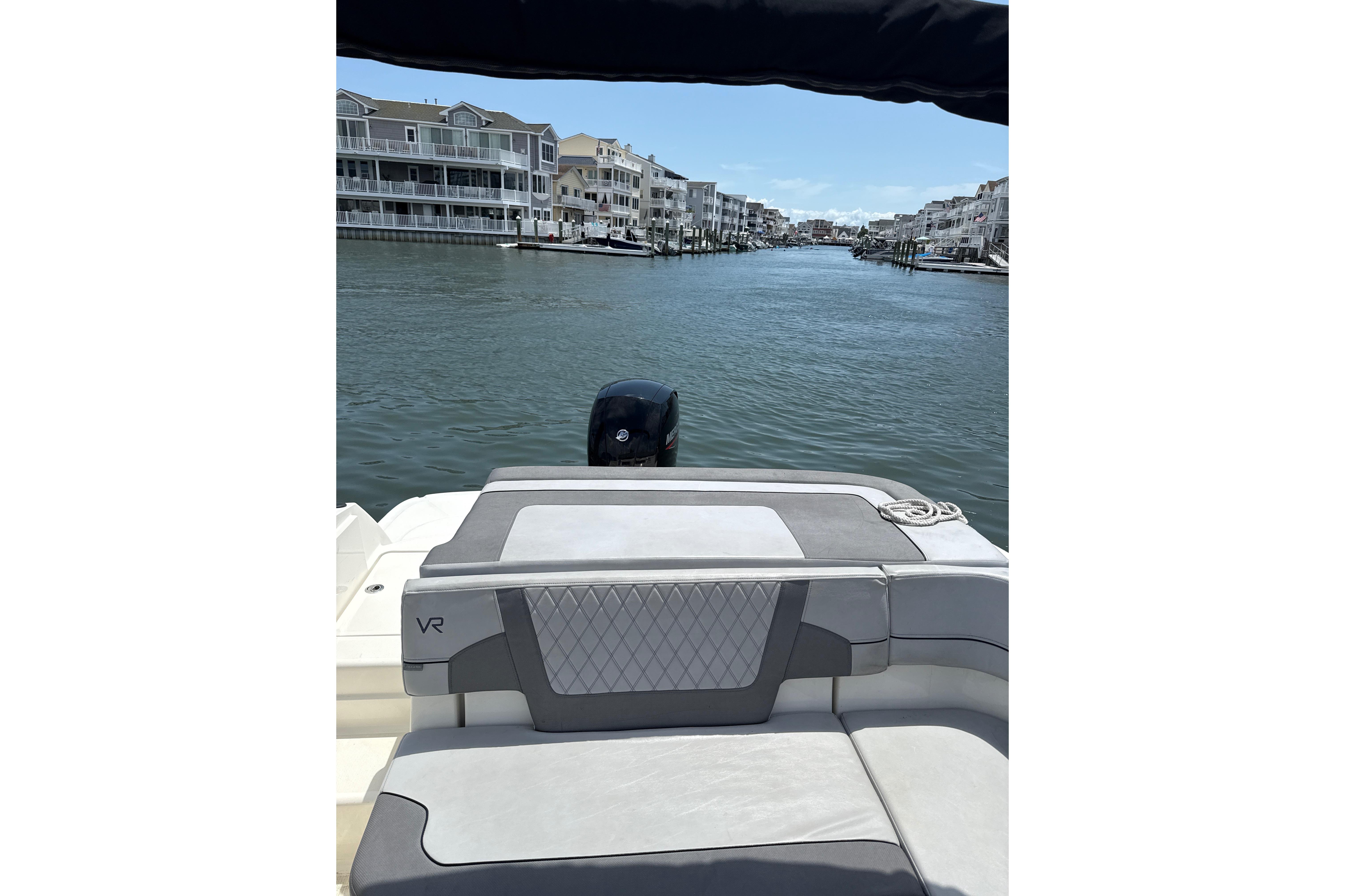 2023 Bayliner VR6 Bowrider OB on a scenic waterfront with modern buildings.