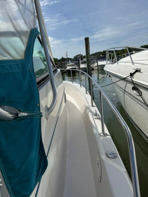 A 1995 Pro-Line 2950 Walkaround boat docked, featuring a blue canopy and stainless steel railing.