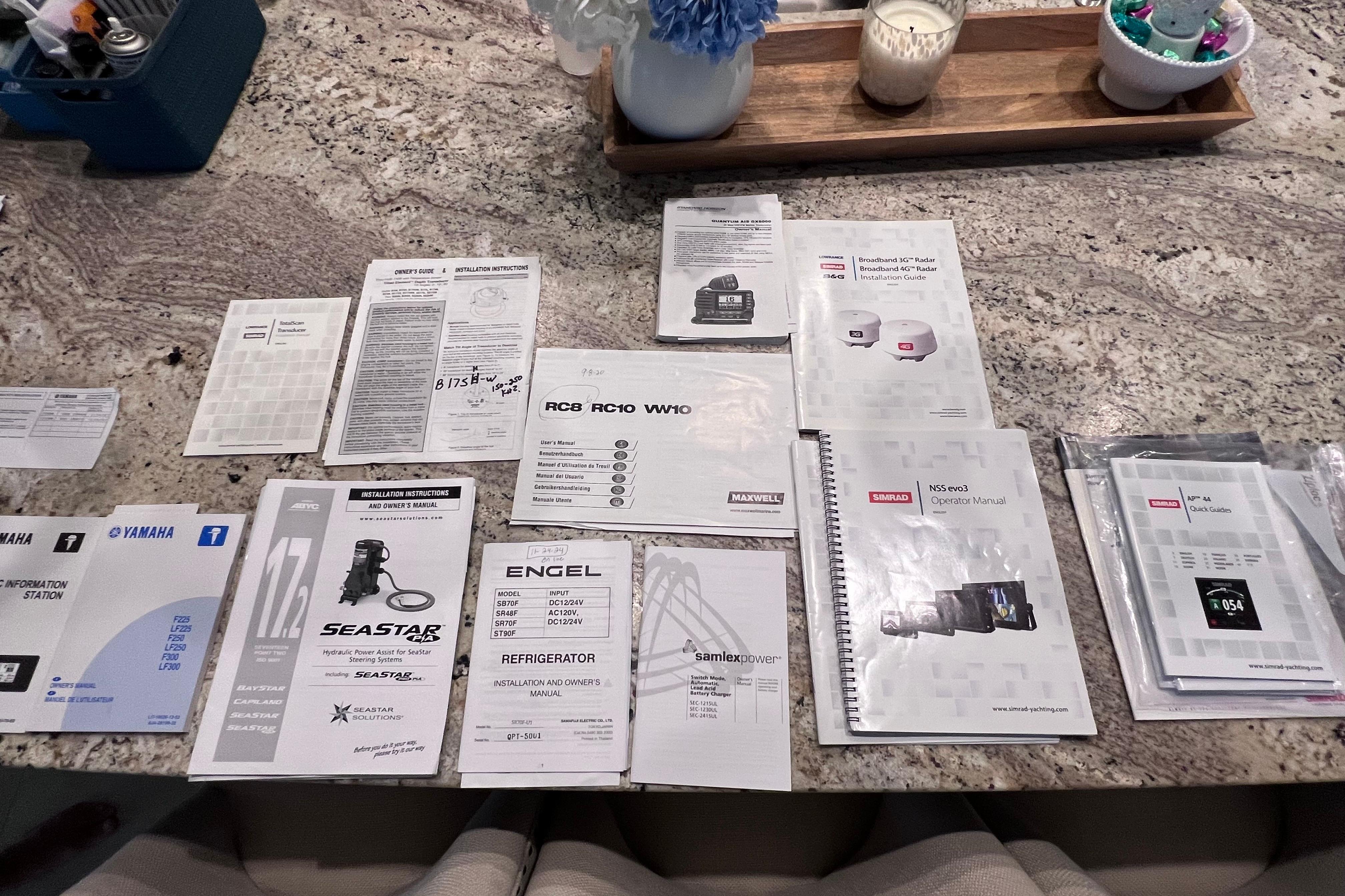 Assorted manuals and guides for a 2005 Pursuit 3070 Offshore boat on a granite countertop.