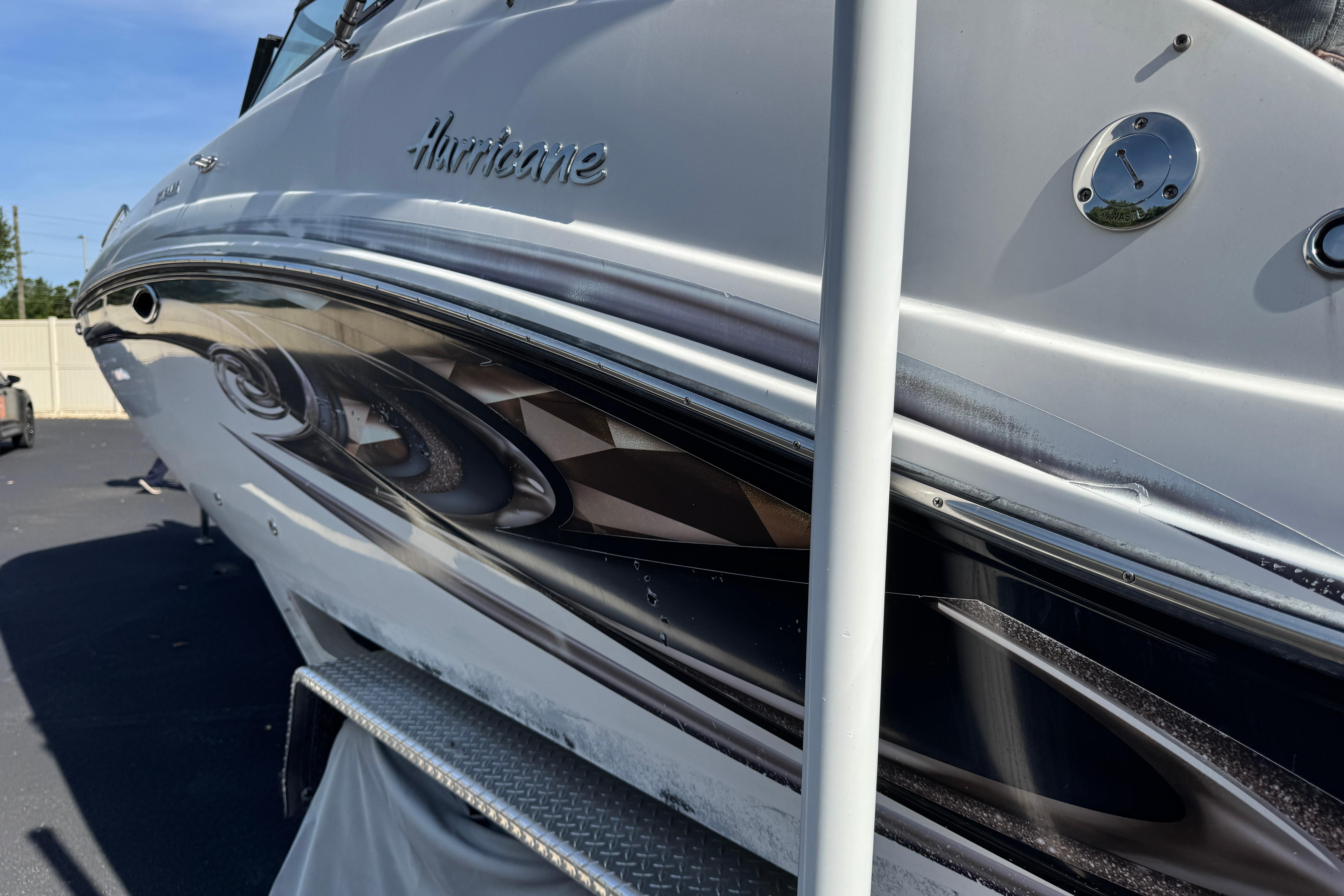 2018 Hurricane SunDeck 2400 OB boat, sleek design, parked on pavement under clear sky.