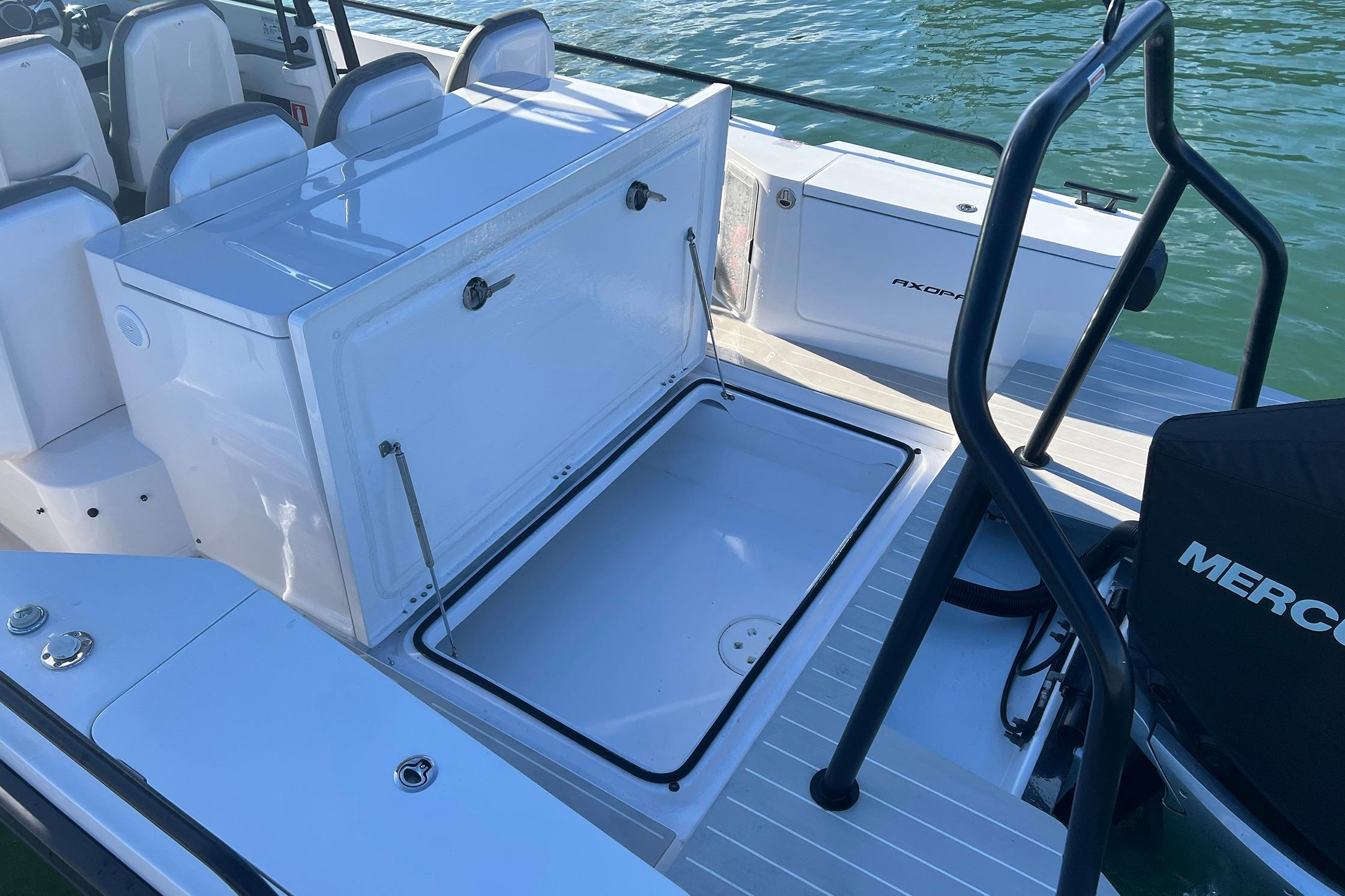 2019 Axopar 28 T-Top boat with open storage compartment, docked on water.