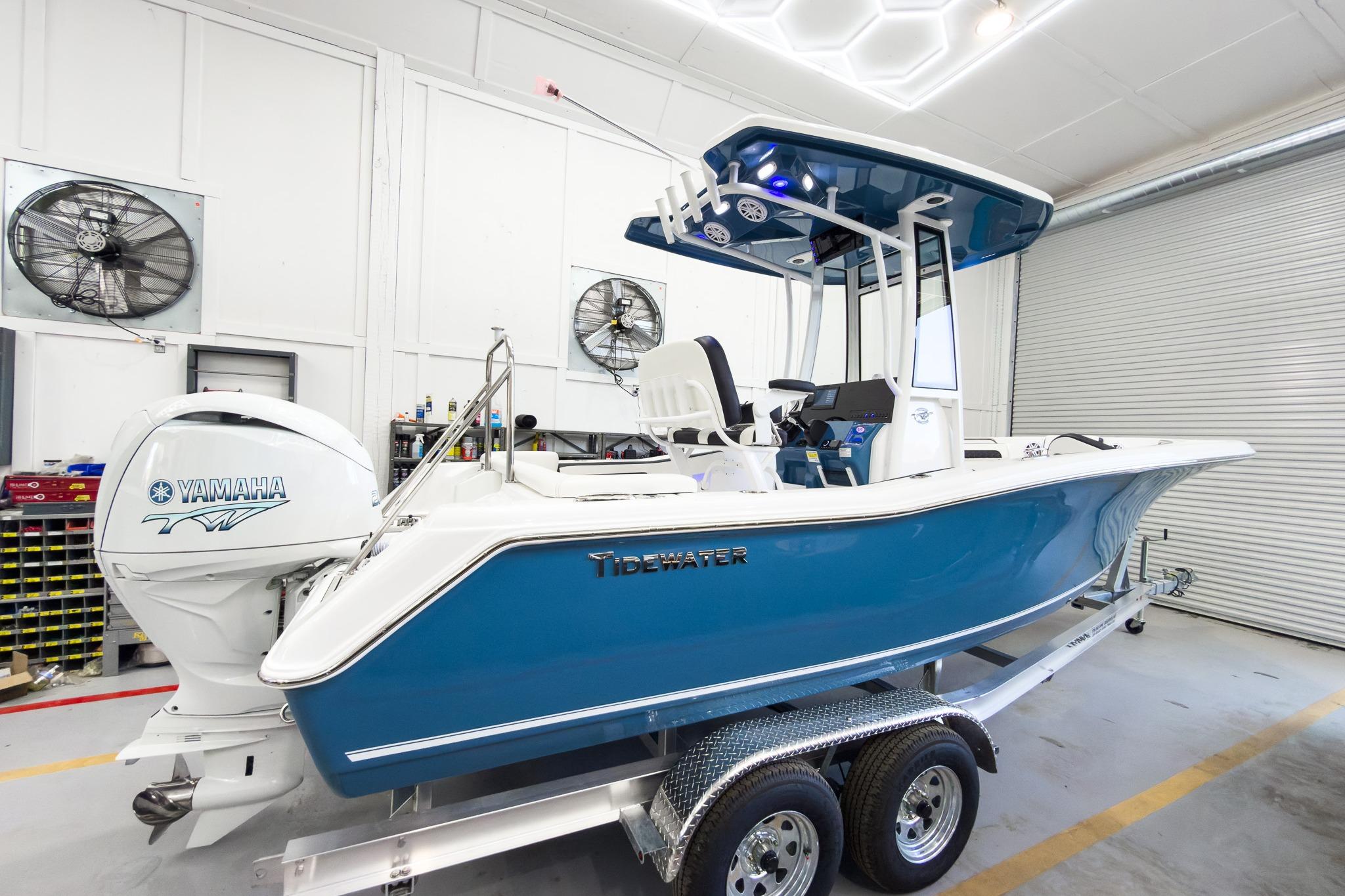 A blue and white Tidewater 220 LXF boat on a trailer in a garage.