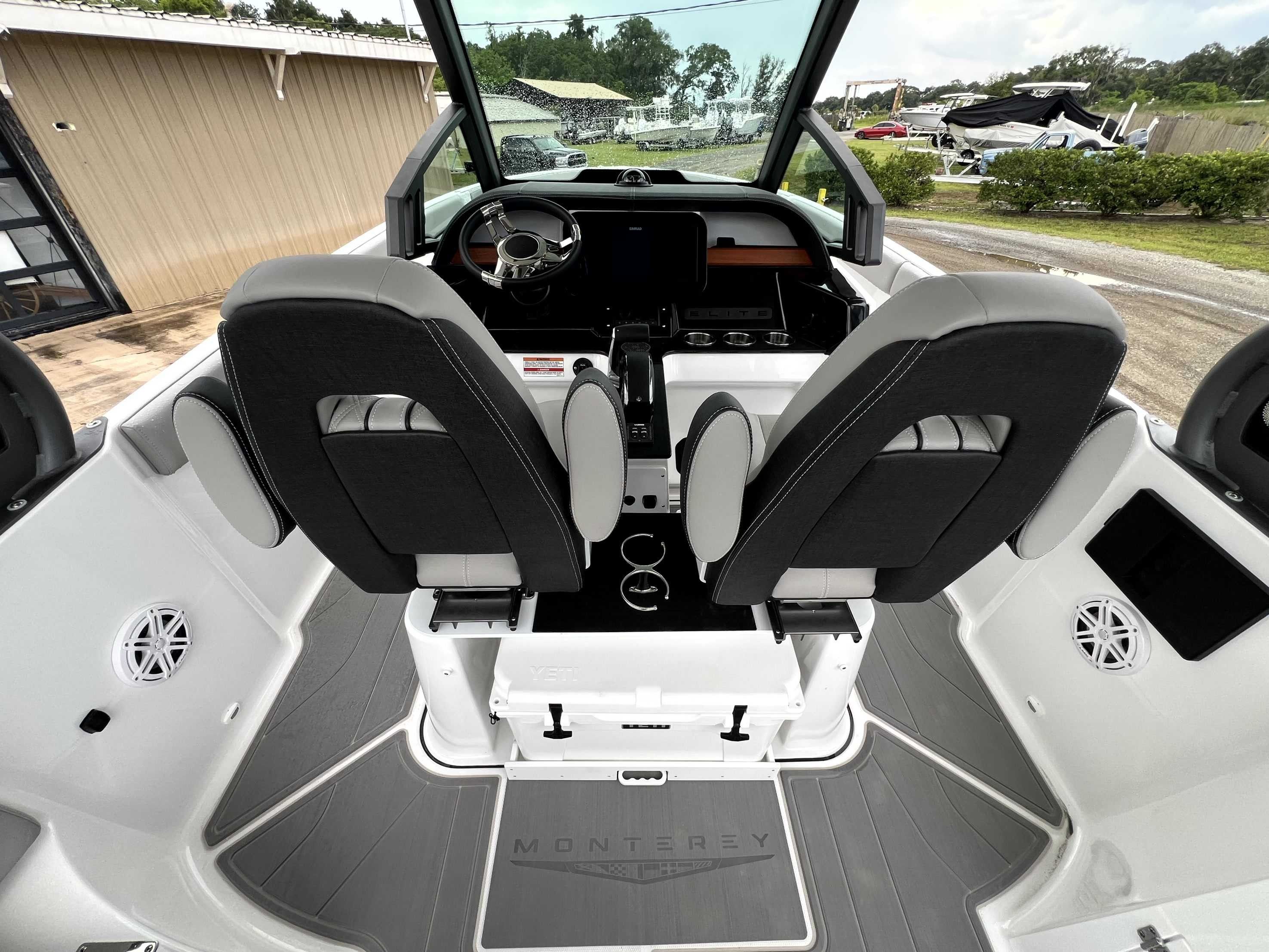 The image shows the cockpit of a Monterey Elite 25 boat with two cushioned seats and a modern helm.