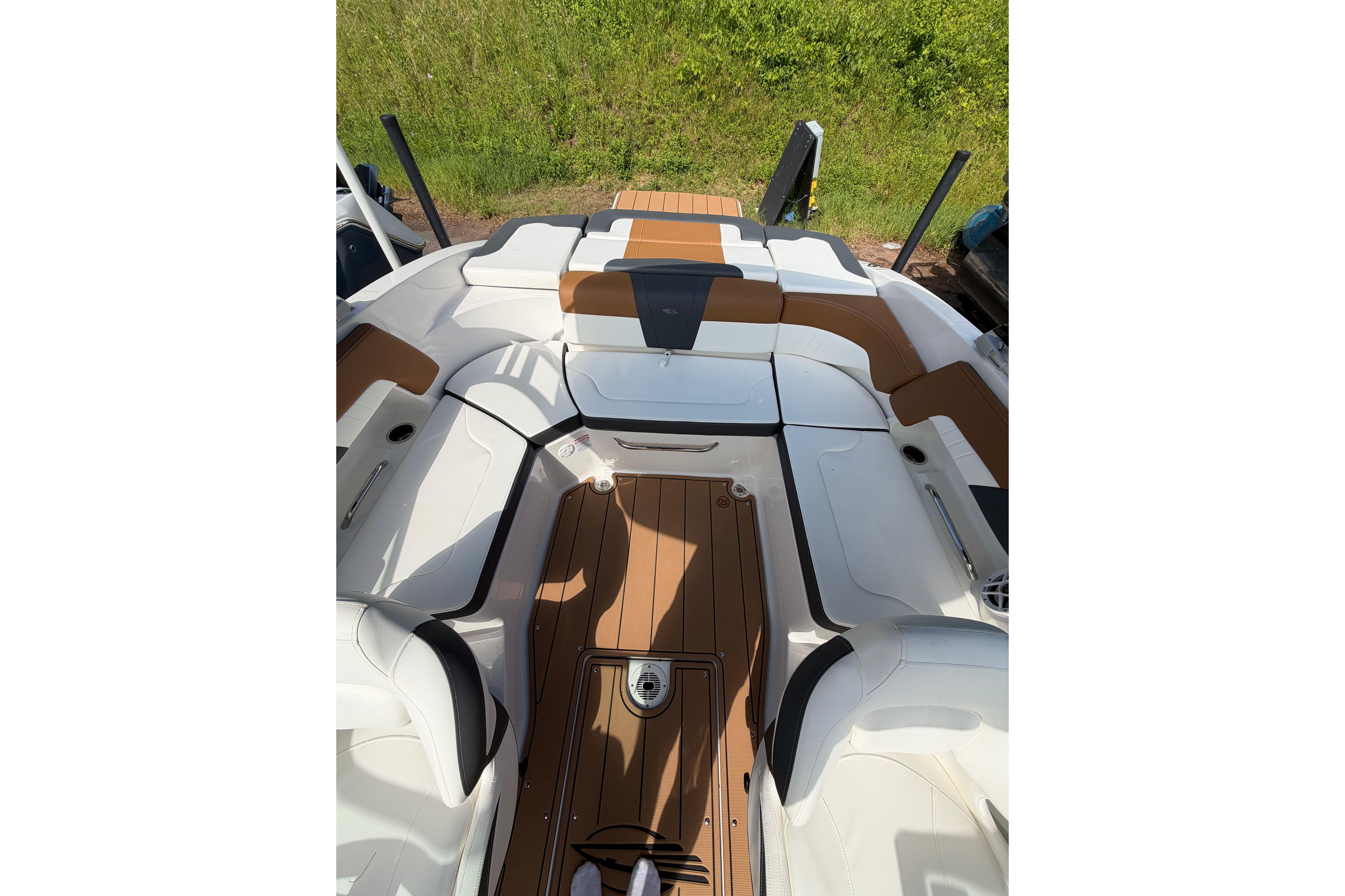 2025 Chaparral 230 SSi boat interior with tan and white seating, wooden flooring.