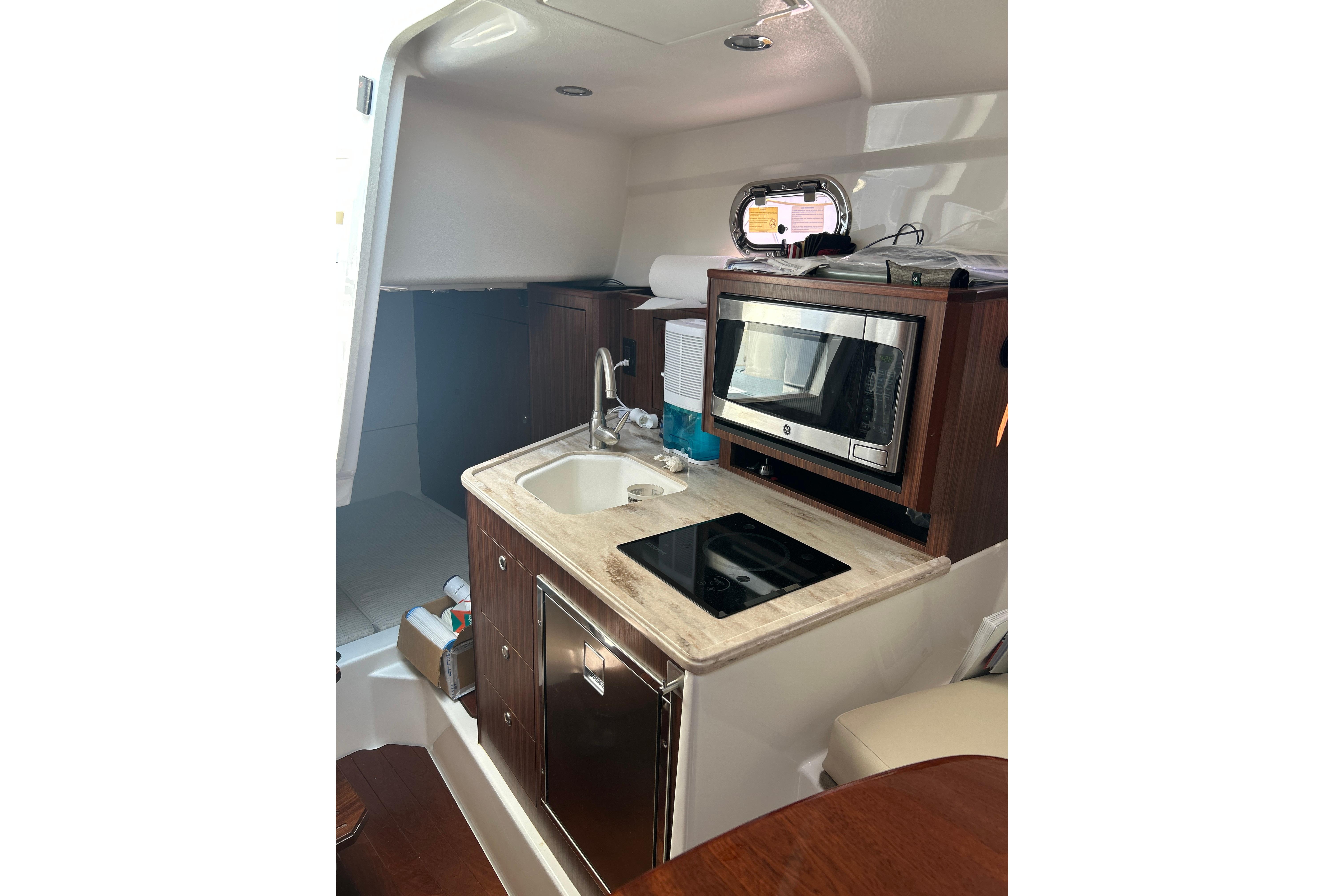 2021 Pursuit OS 325 Offshore boat interior kitchen with sink, stove, and microwave.