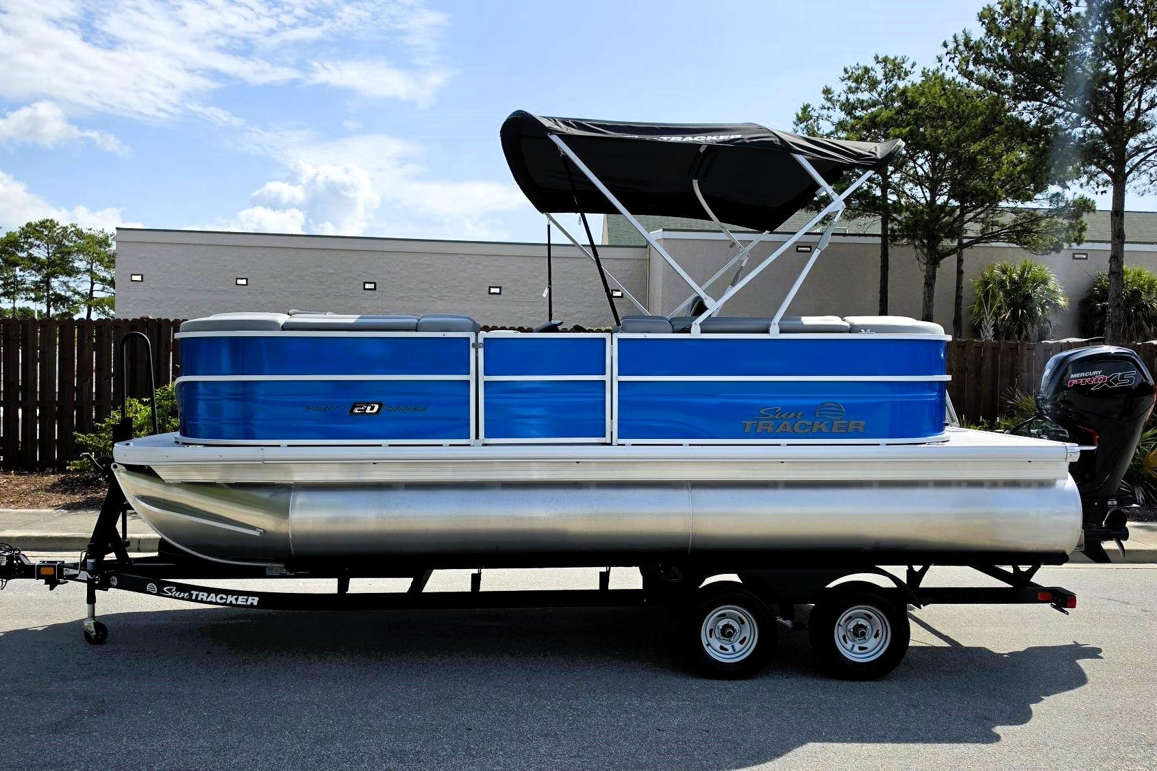 2026 Sun Tracker Party Barge 20 DLX pontoon boat on trailer, blue and silver design.