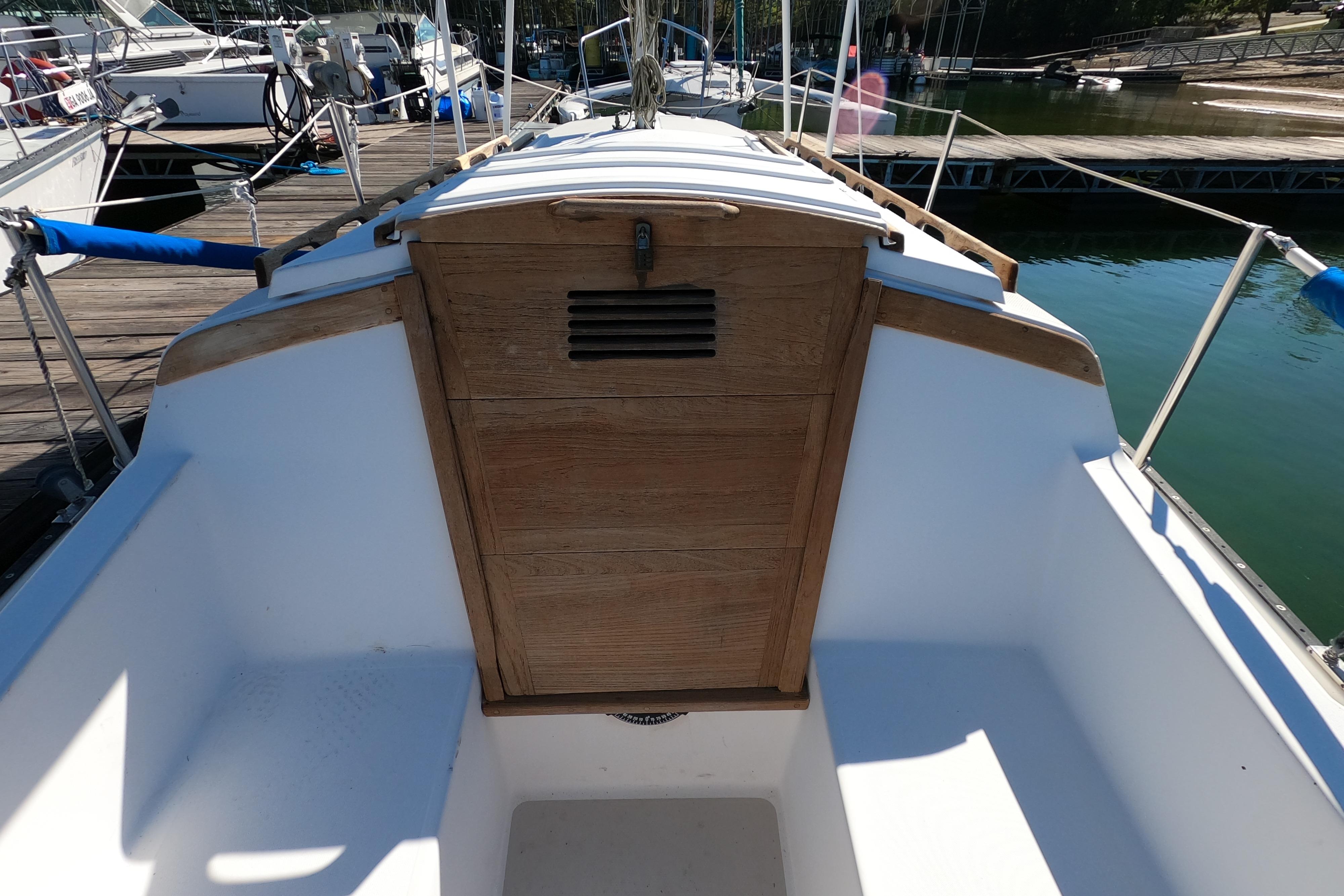 1983 Catalina 25 sailboat cockpit with wooden hatch, docked at marina.