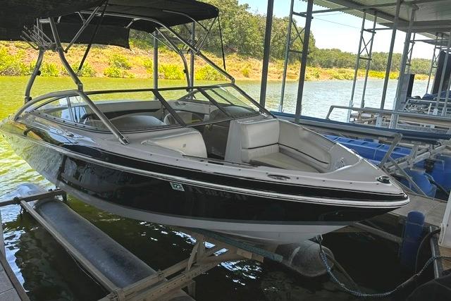 2007 Four Winns 200 Horizon boat docked on a lift by a scenic lake.