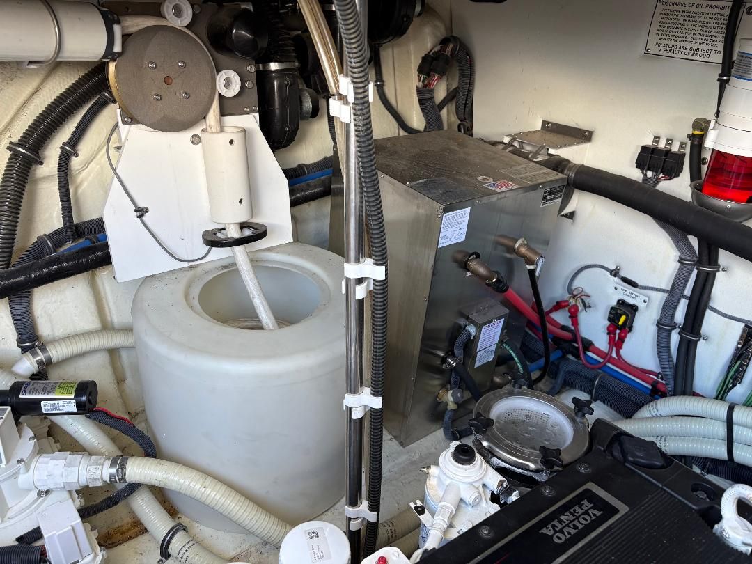 Engine room of a 2011 Formula 45 with hoses, cables, and a water tank.