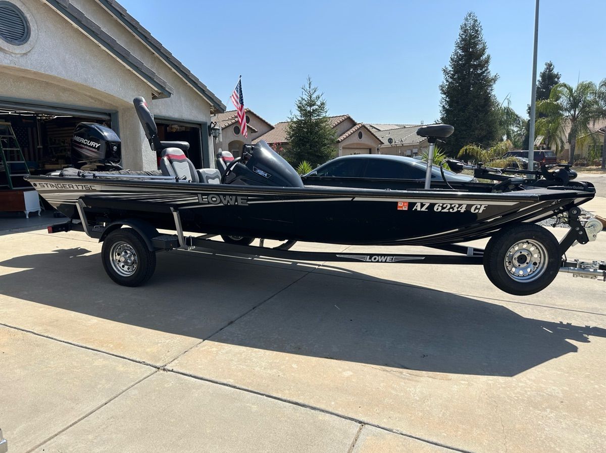A black 2018 Lowe Stinger 175C boat on a trailer in a driveway.