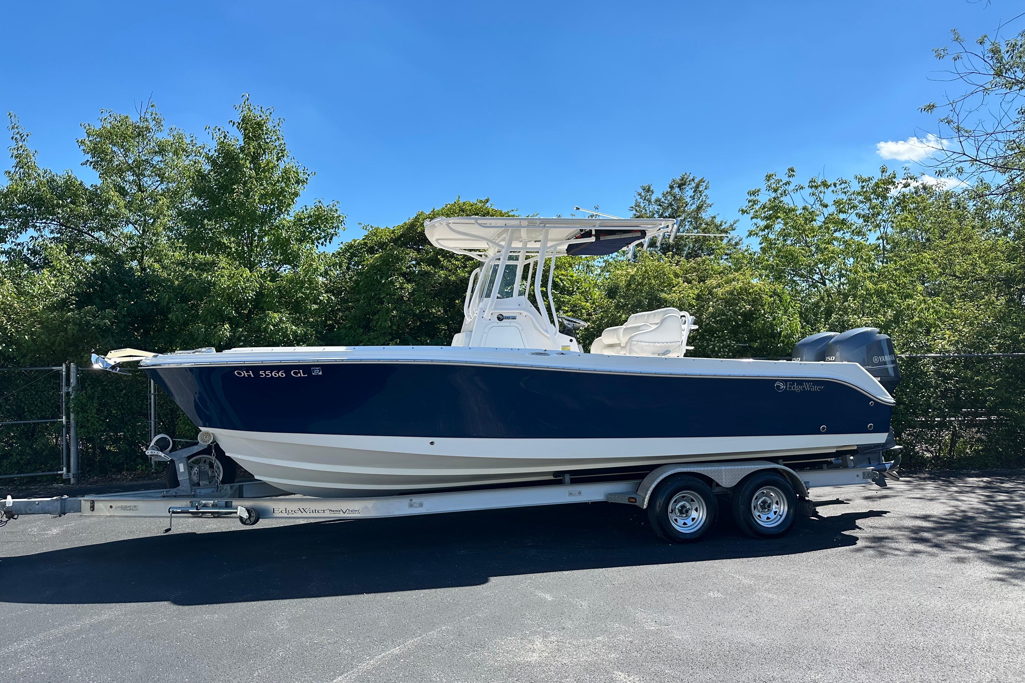 2015 Edgewater 245CC boat on trailer, parked outdoors under clear blue sky.