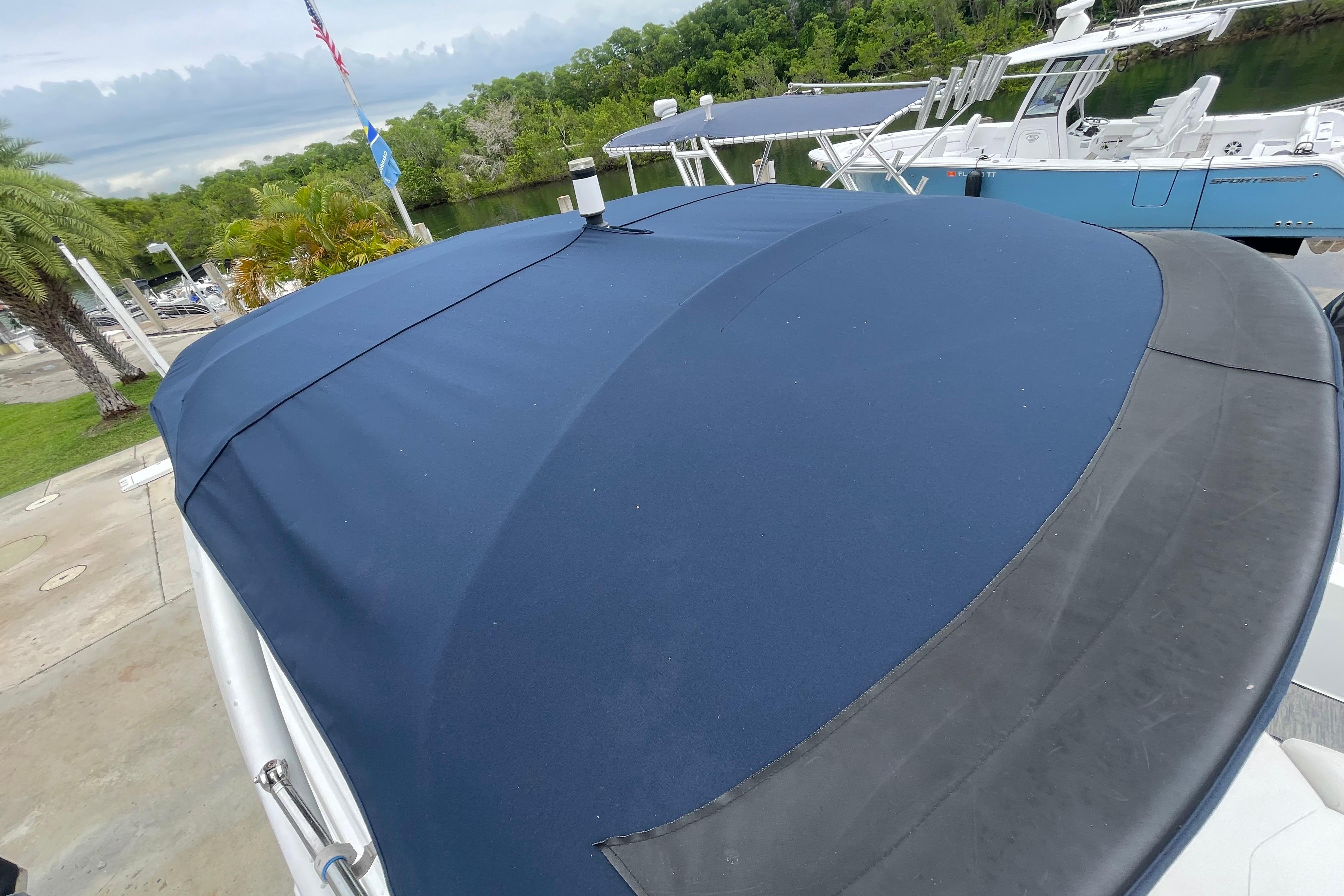 2022 Four Winns HD8 OB boat with blue cover docked near lush greenery.