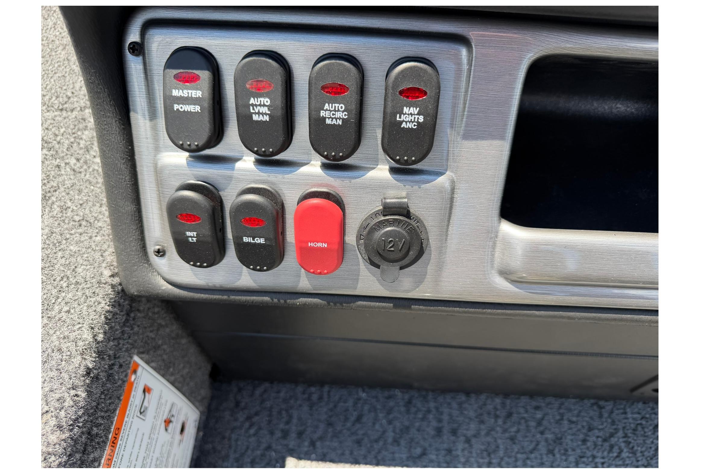 Control panel of 2027 Lund 1875 Pro Guide boat with various switches and a 12V outlet.