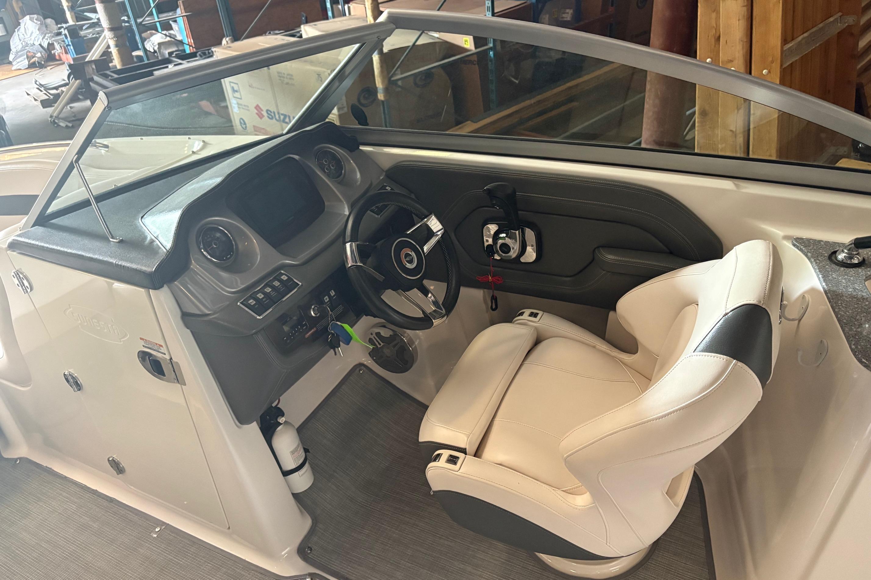 2016 Chaparral 244 Sunesta boat cockpit with steering wheel and white captain's chair.