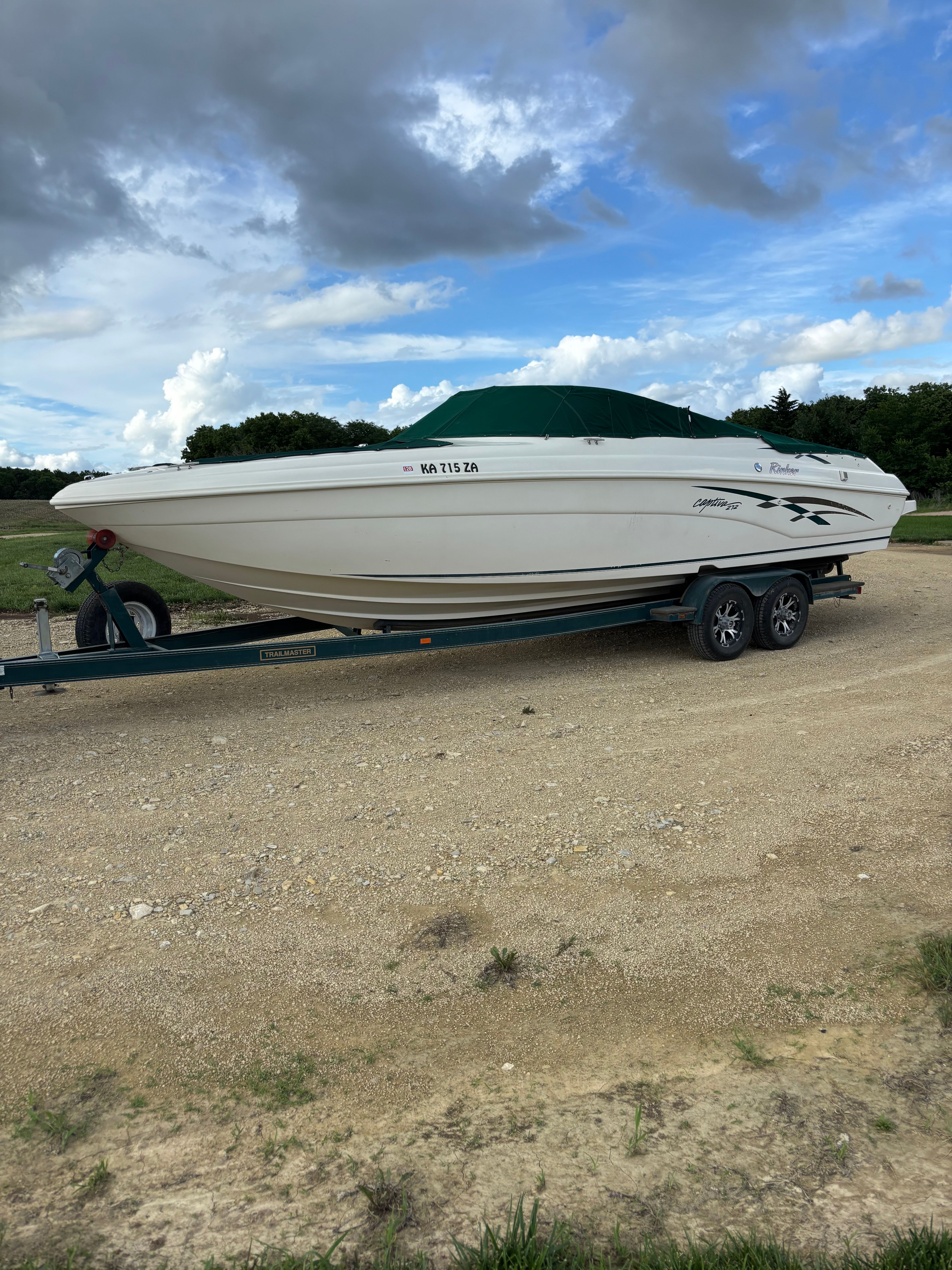 1999 Rinker Captiva 272 boat on trailer, cloudy sky.