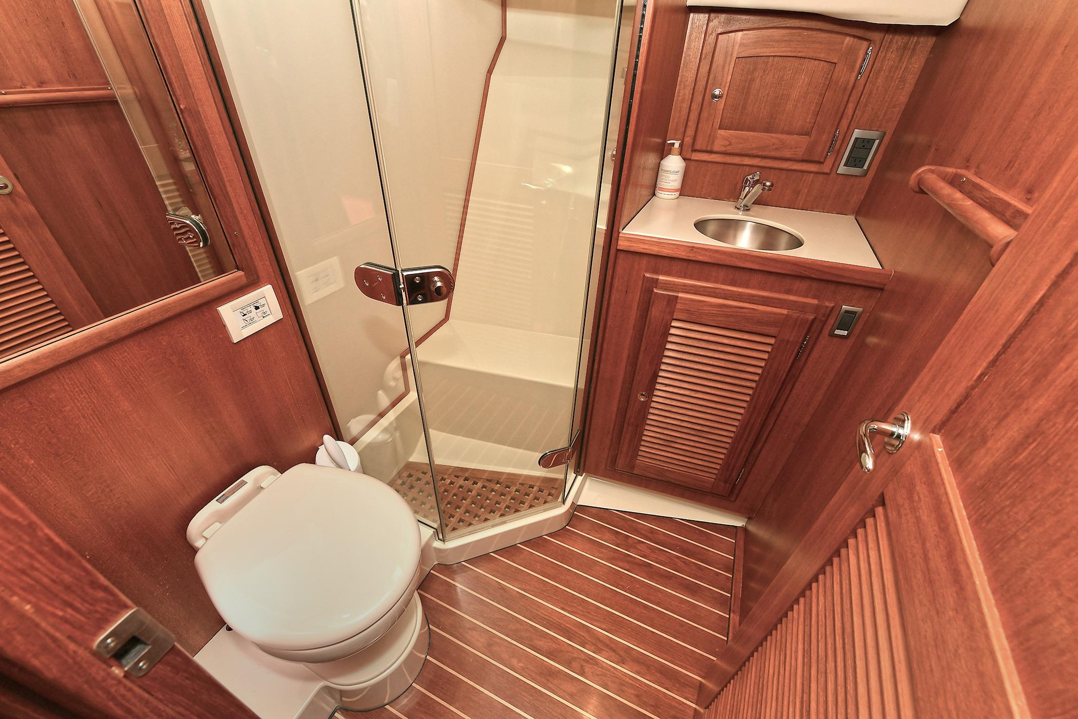 Luxurious 2005 San Juan Downeast Express yacht bathroom with wood finish and modern amenities.