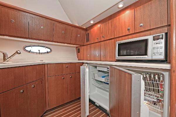 2008 Tiara Yachts 4200 Open galley with wood cabinets, microwave, and open fridge.