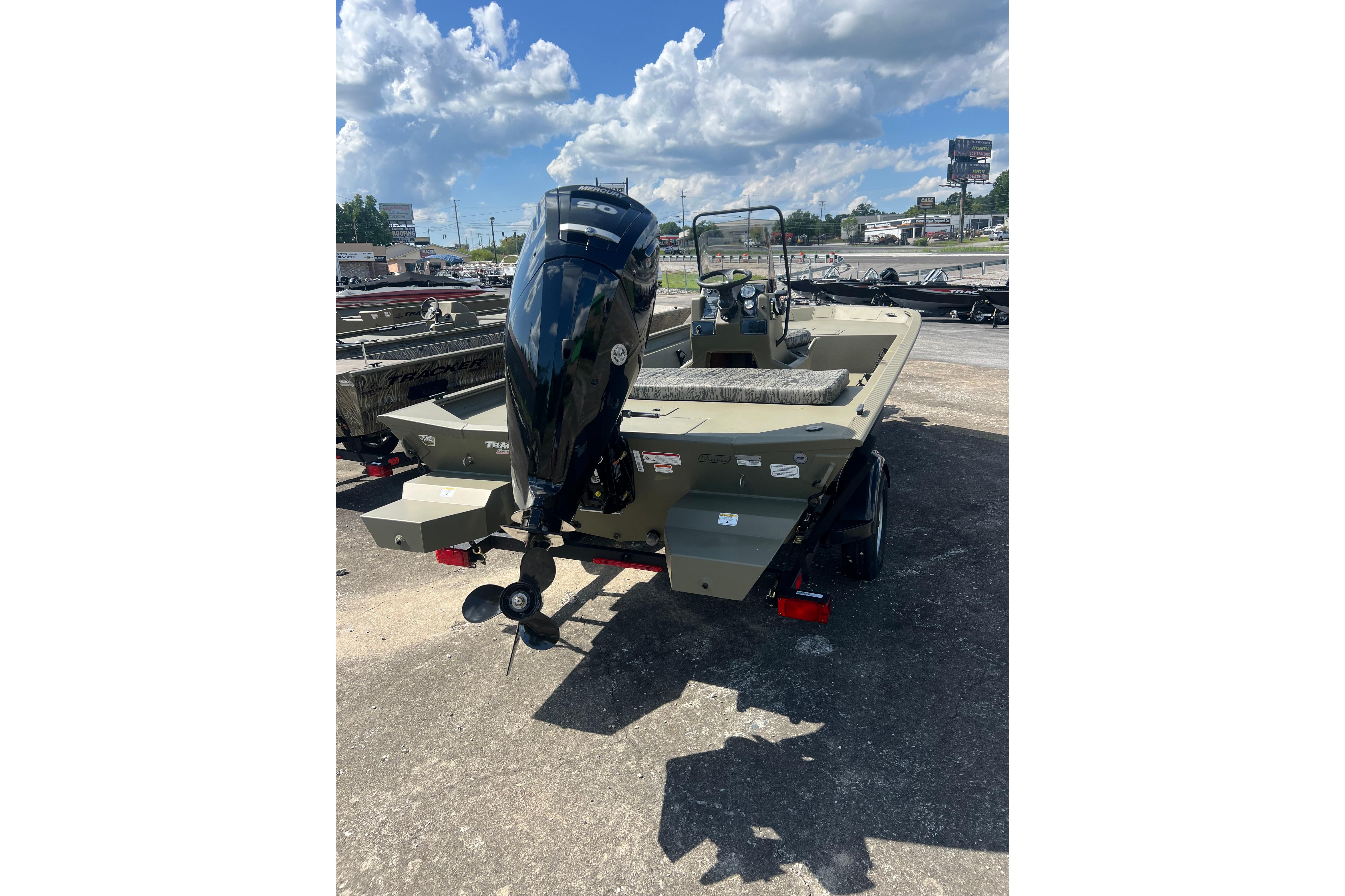 2026 Tracker Grizzly 1860 CC boat with outboard motor, parked outdoors under a cloudy sky.