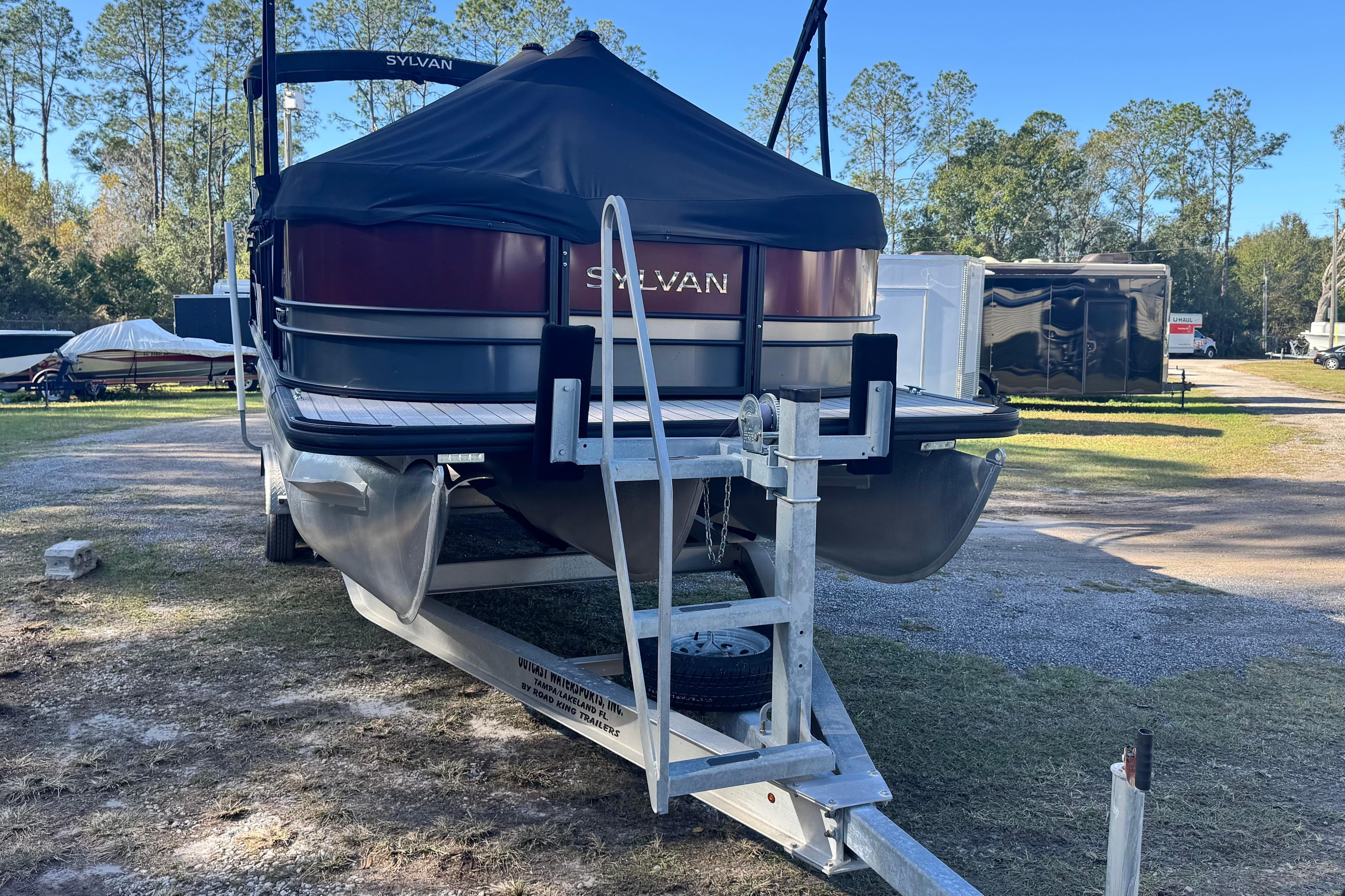 2023 Sylvan L5 CLZ pontoon boat on trailer, covered, in outdoor storage area.