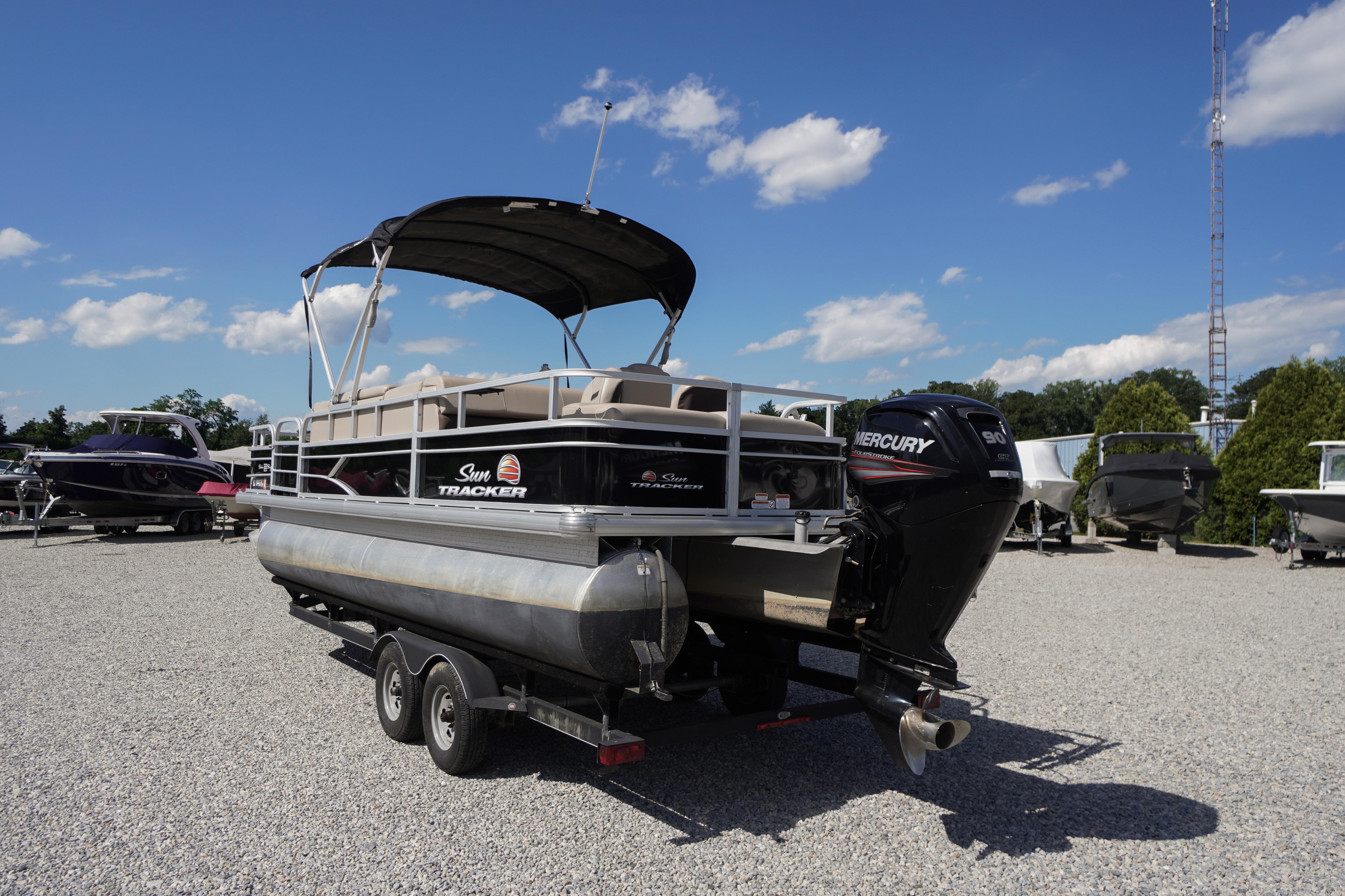 2019 SUNTRACKER Fishin' Barge 22 DLX pontoon boat on trailer, under clear blue sky.