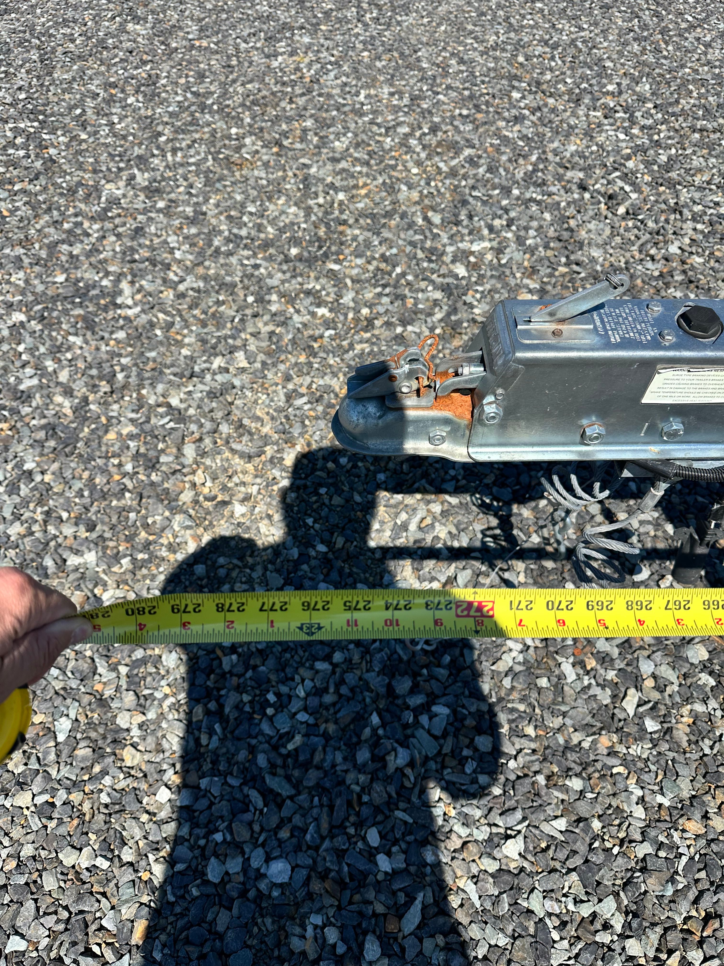 Close-up of a boat trailer on gravel with a measuring tape.
